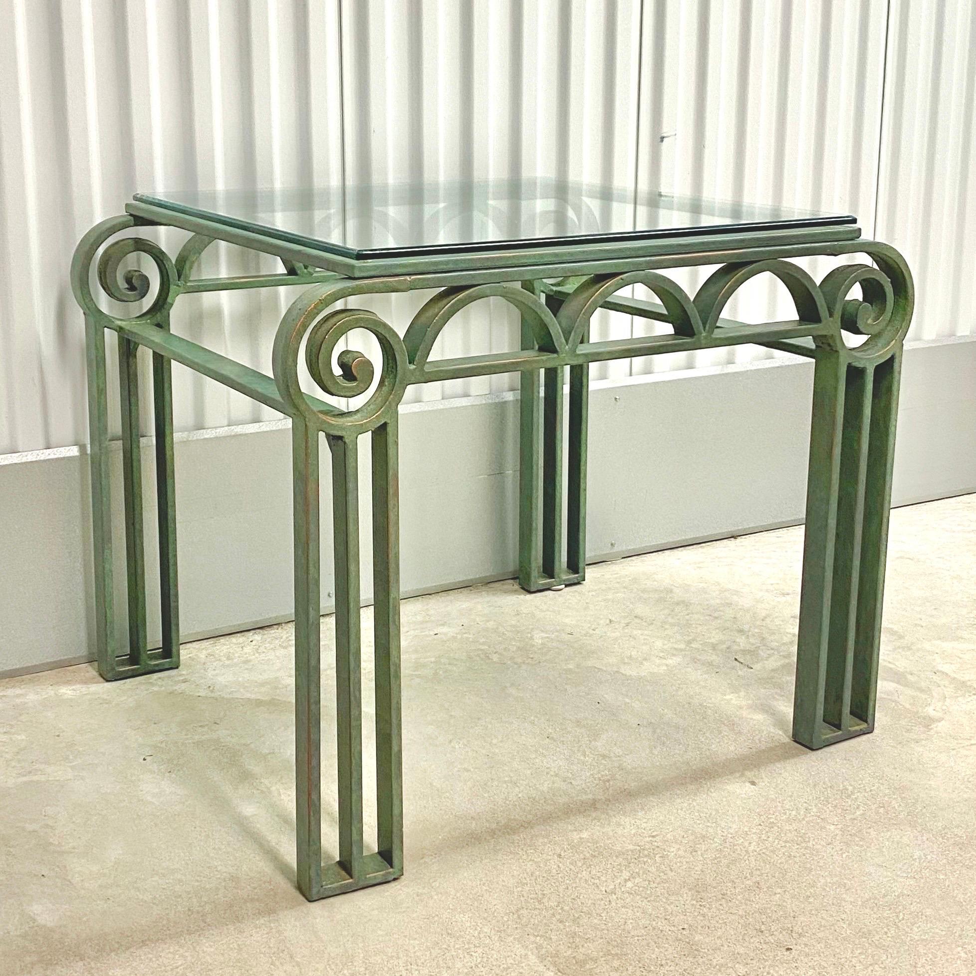 Vintage circa 1990s iron table with verdigris finish. Green painted iron with column legs meeting scrolled corners and half moon apron. Glass top. Available matching coffee table available separately as seen in the last image.