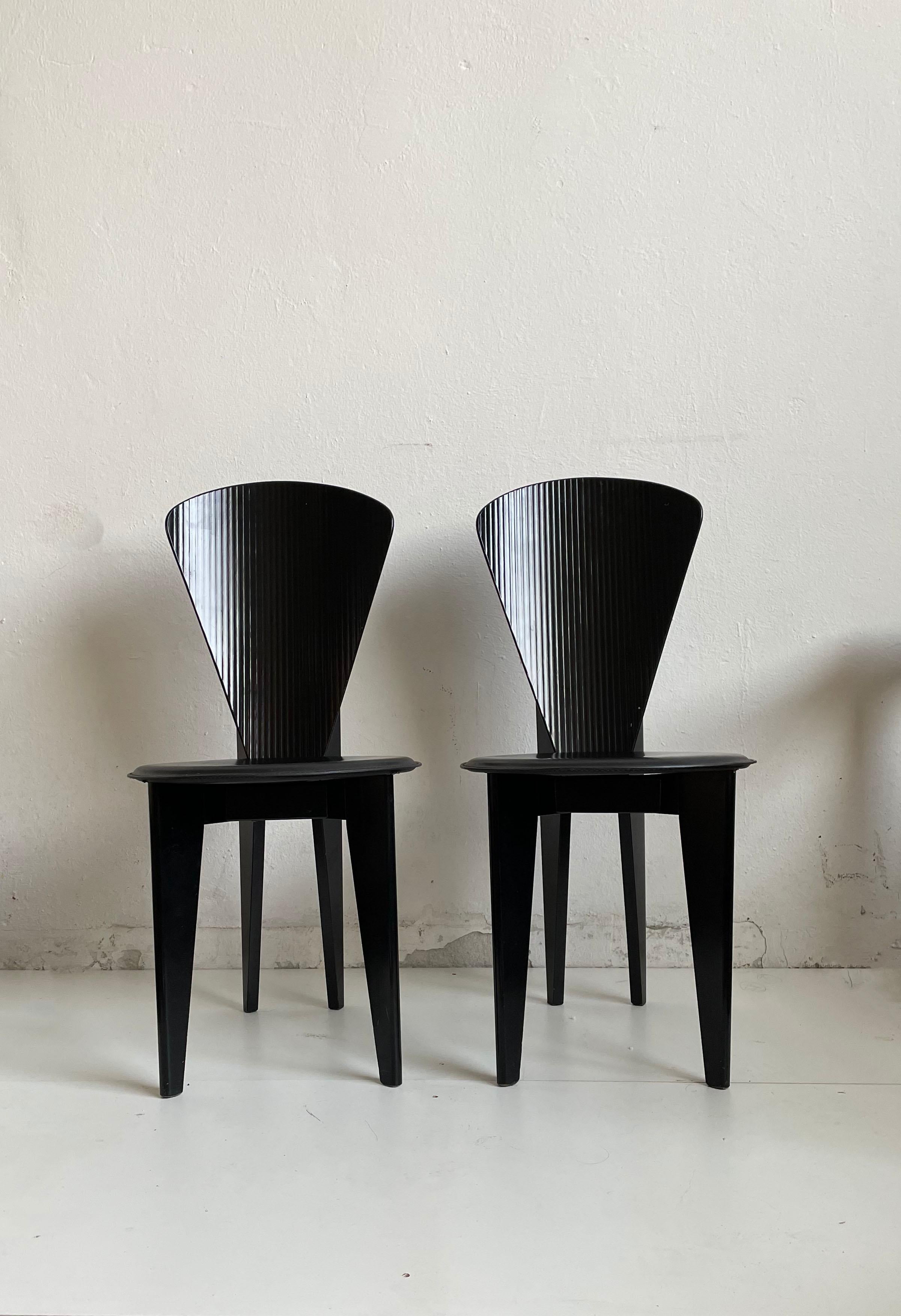 This set of two black wooden dining chairs by Calligaris was made in Italy, circa 1980.

Stunning sculptural postmodern design. These dining chairs feature a curved back with ridges and round leather seats.

There are no structural issues. The