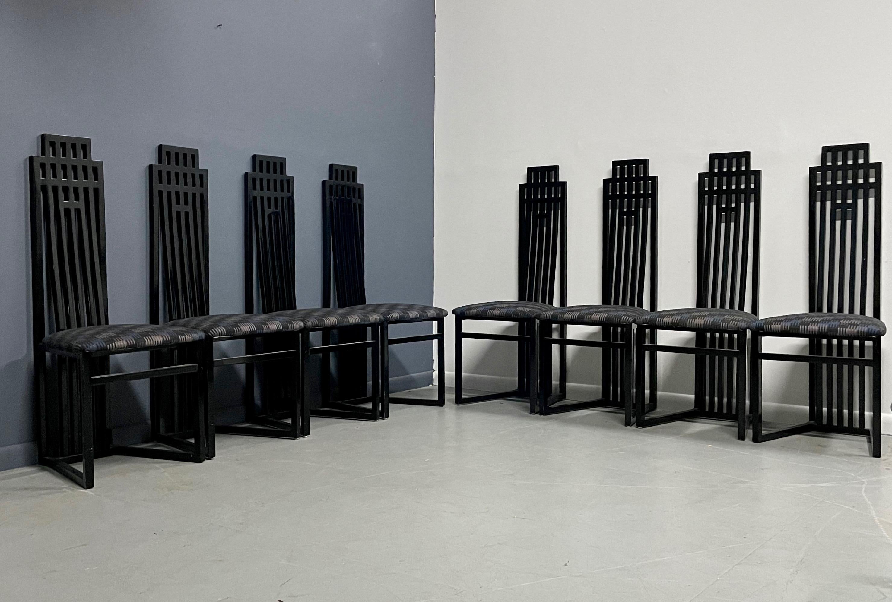 Eight sculptural dining chairs in black lacquer with a sky scraper motif. These chairs are upholstered in period fabric that is in wonderful condition.