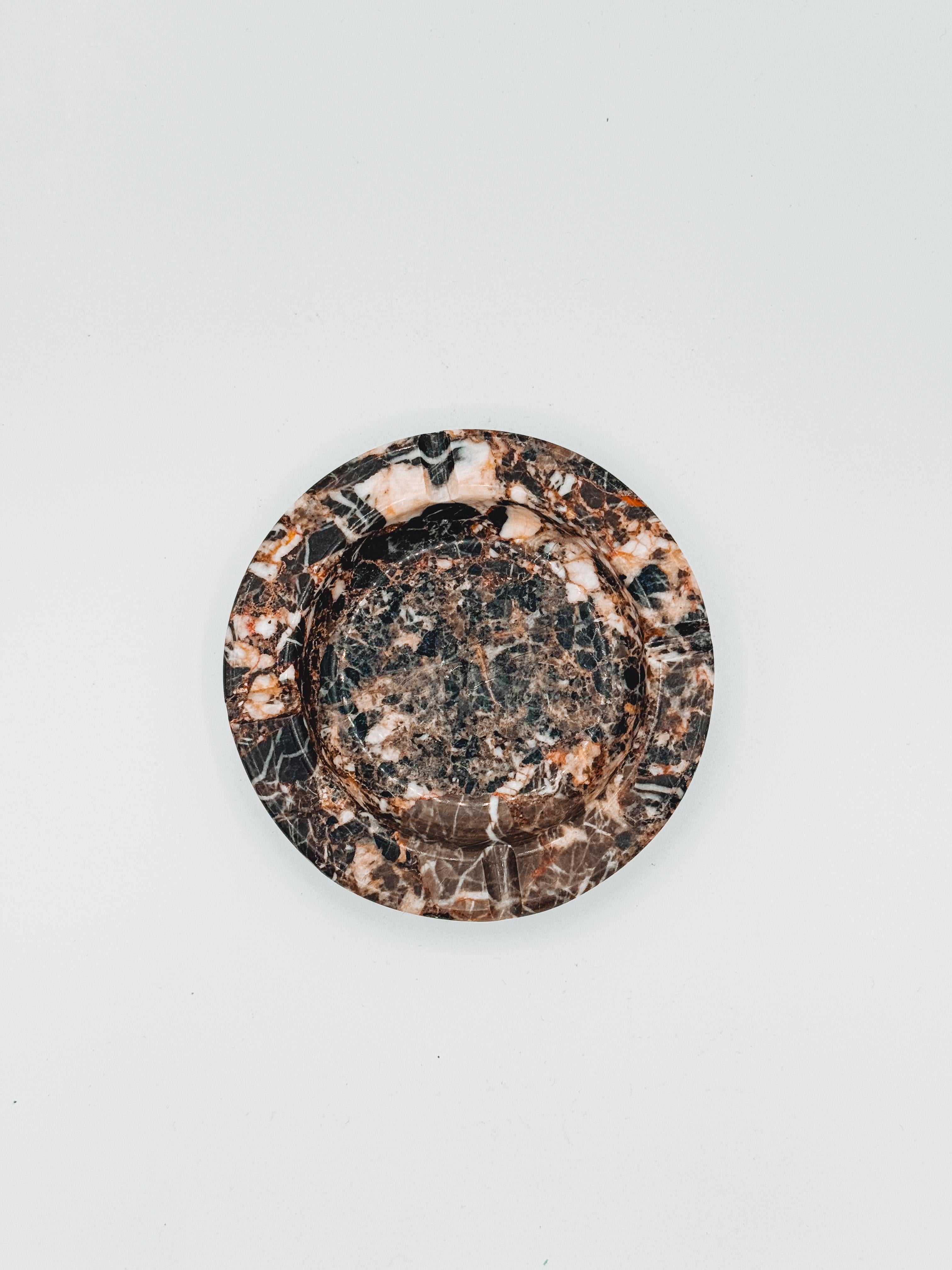 This exquisite postmodern marble ashtray, crafted in Italy during the 1980s, features a captivating blend of black, brown, white, cream, and pink hues. The turned marble showcases unique veining and colour variations, making it a standout piece for