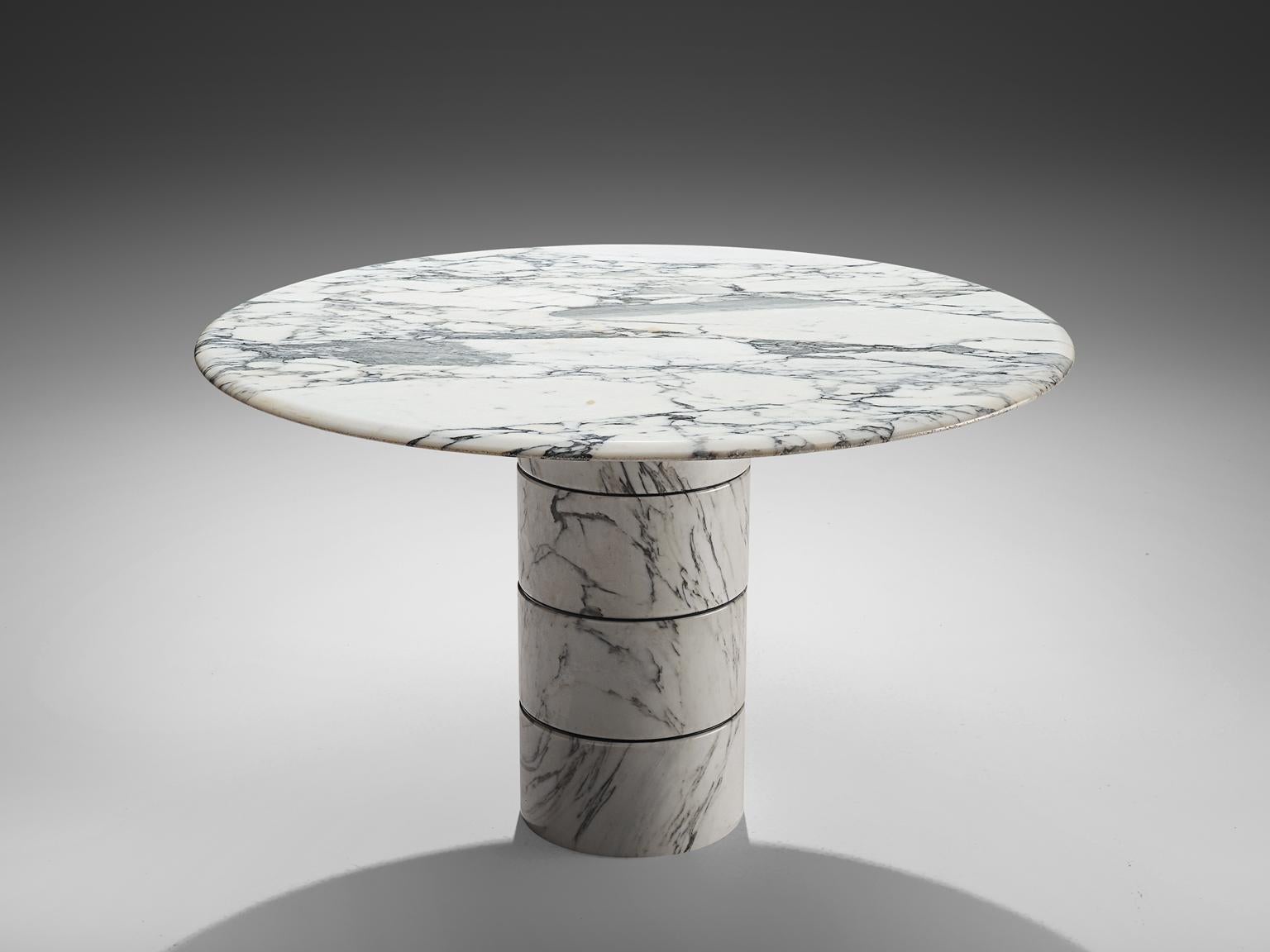 Dining table, marble, Italy, 1970s. 

This architectural table is a skillful example of postmodern design. The circular table has a soft edges edge and rests on a thick, robust single foot. This foot features no joints or clamps and is