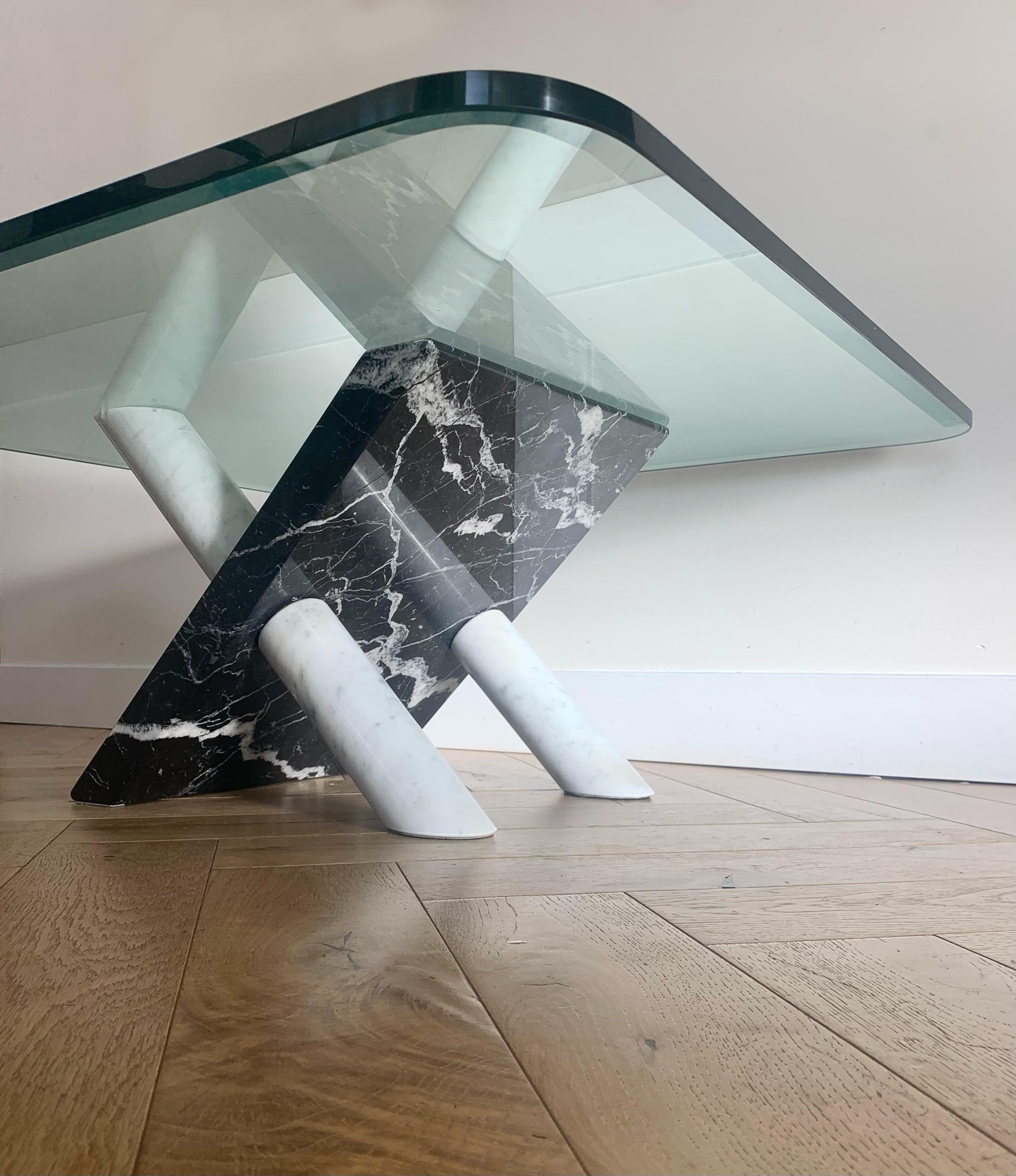 An incredibly unique sculptural marble coffee table with thick glass top by Cattelan Italia, circa late 1970s or early 80s. White carrera marble cones pierce a noir marquina slab, upholding a .75” thick piece of curved beveled glass. Some losses to