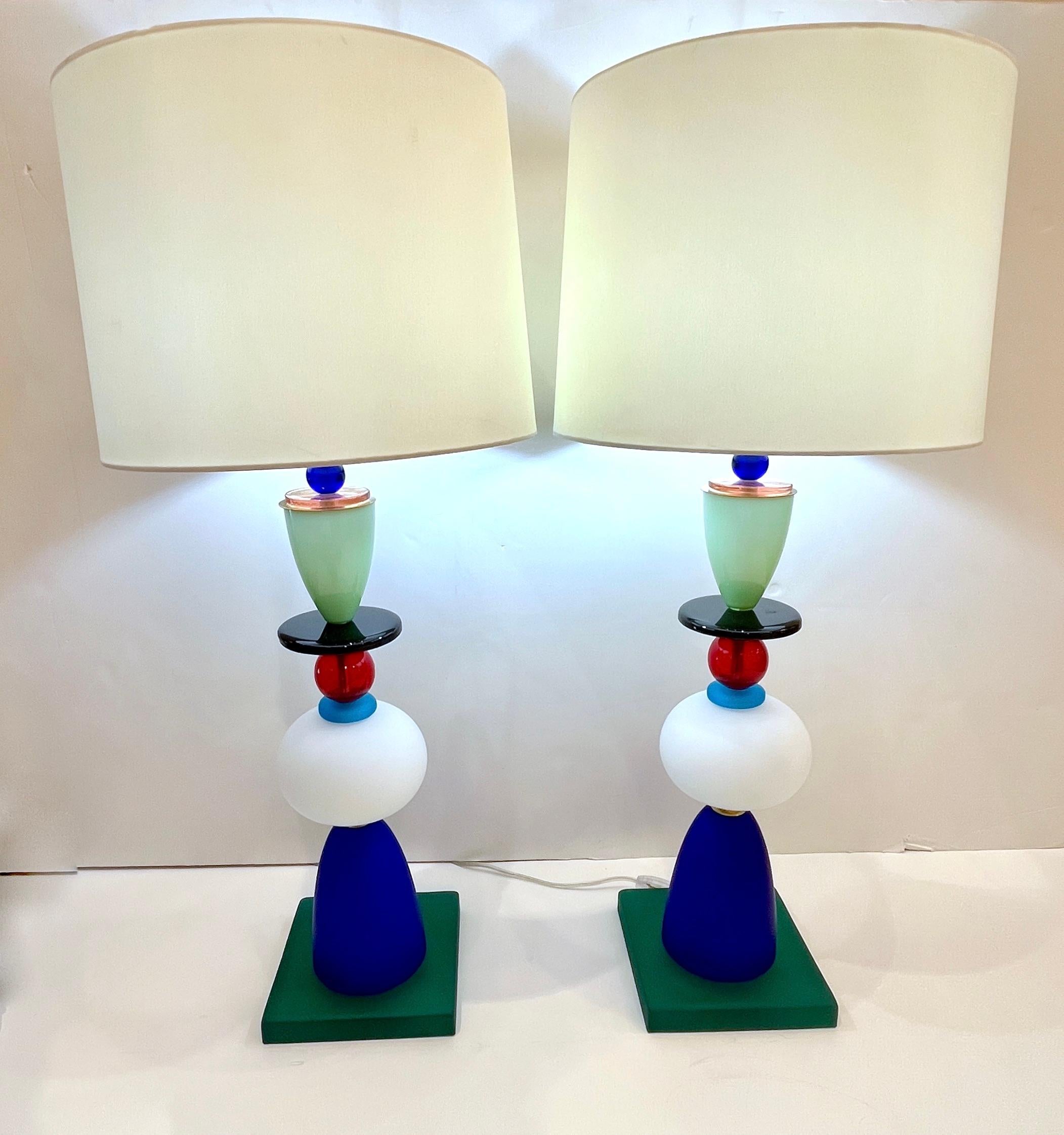A 1980s unique pair of Italian colorful Murano glass lamps in the style of Ettore Sottsass for Memphis. Constructed with tiers of highly vibrant and geometrical colored blown Murano glass, each layer strategically placed for color and organic
