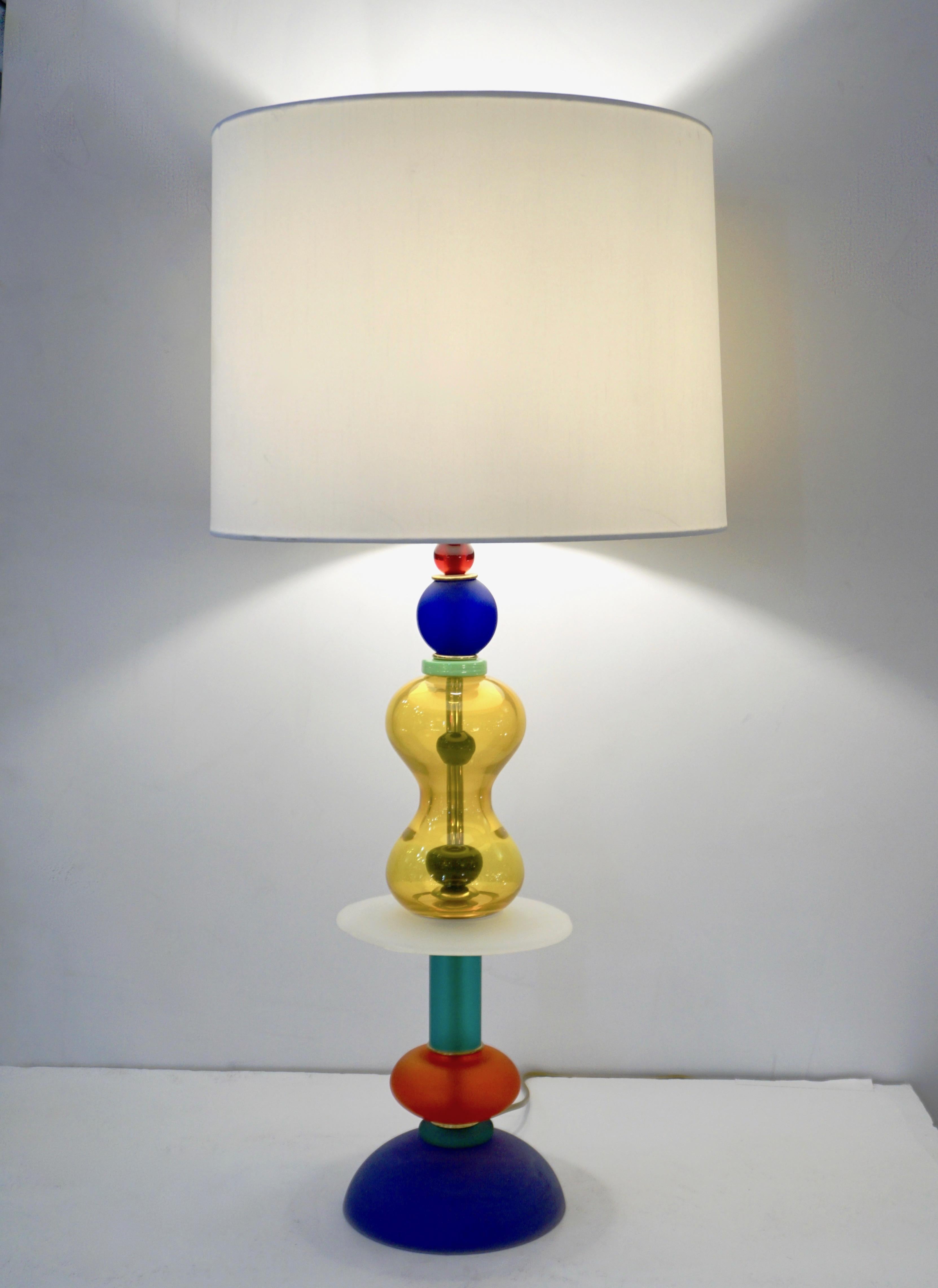 A 1980s unique pair of Italian colorful Murano glass lamps in the style of Ettore Sottsass for Memphis. Constructed with tiers of highly vibrant and geometrical colored blown Murano glass, each layer strategically placed for color and organic