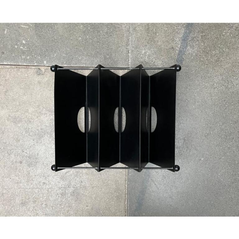 Postmodern magazine rack from Memphis based on a design by Ettore Sottsass from the 80s. Unfortunately there is no real source for this.

A modular design that can be designed flexibly. The design consists of three V-shaped angled metal elements and