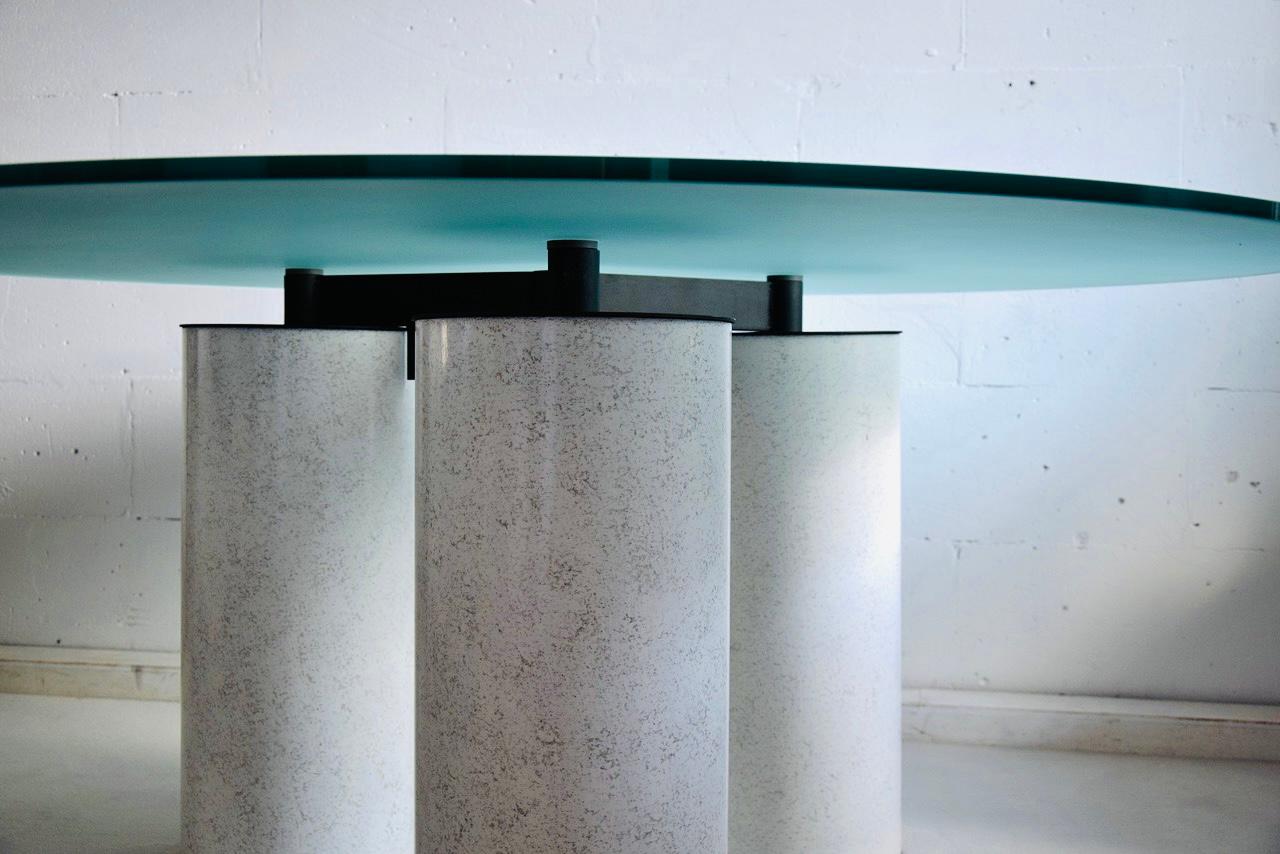 Big and impressive Italian made dining table designed by Lella and Massimo Vignelli. This award-winning table is part of series first designed in 1985 for Acerbis. 
The opalescent round crystal top is supported by 3 oversized metal columns.
This