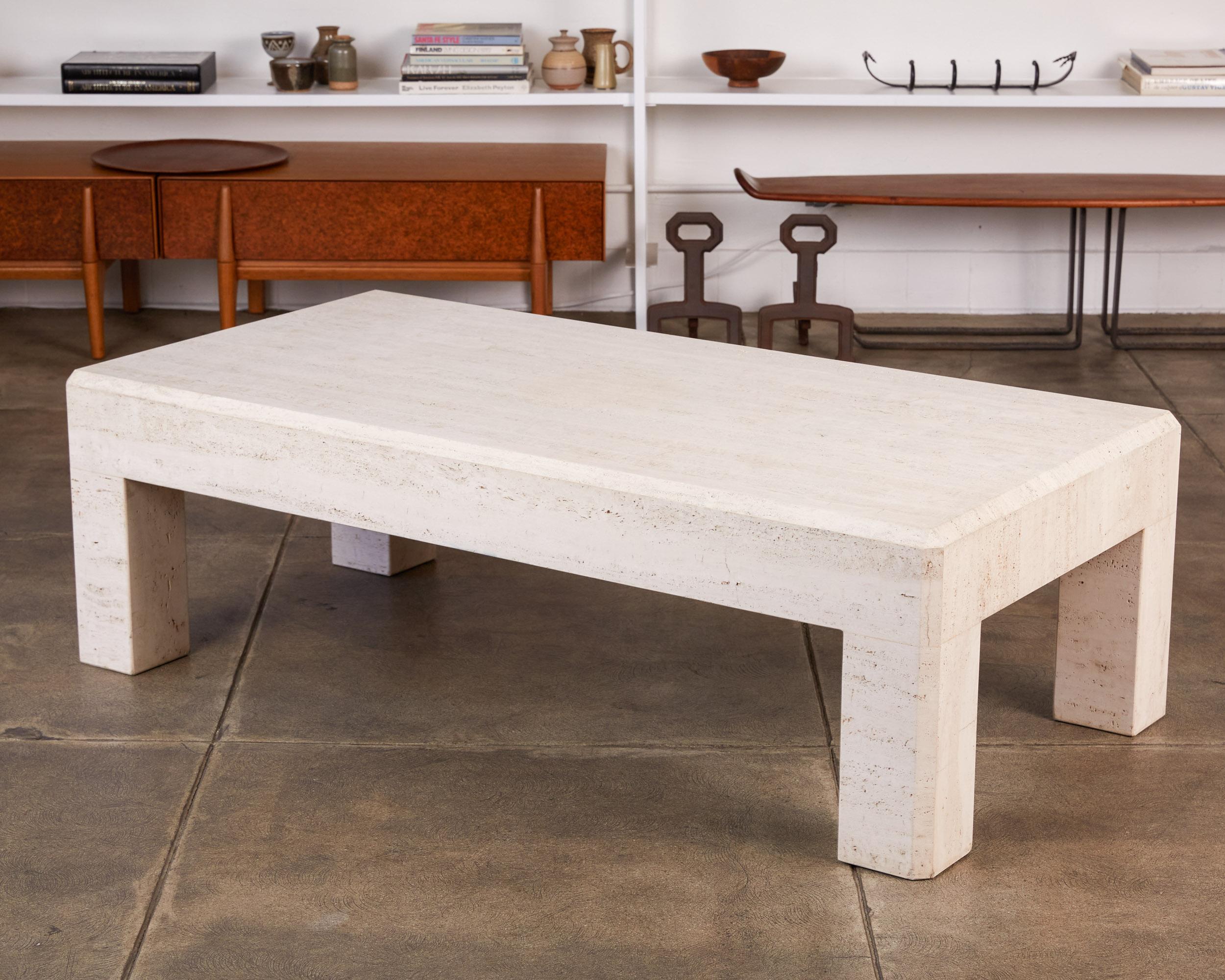 Postmodern travertine coffee table, Italy, circa 1980s. This rectangular table has a thick travertine top, that sits atop four square column legs, featuring a chamfered edge detail. With a sleek shape that is reminiscent of tables designed by