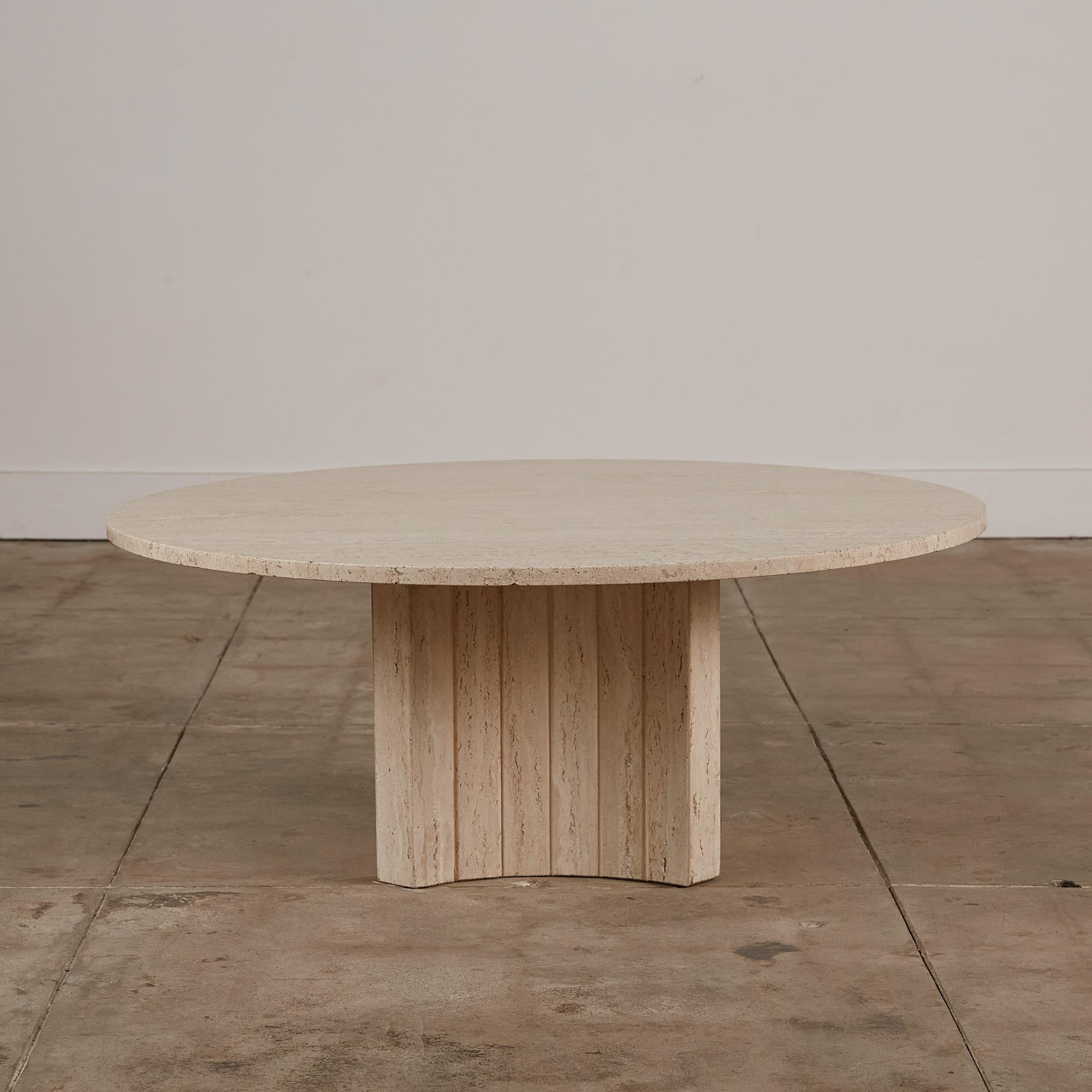 This travertine coffee table, while almost monolithic in size doesn’t take over a space but rather acts as a compliment to those pieces surrounding it. The travertine top has a matte finish and flat edge. The circular top rests on a four sided