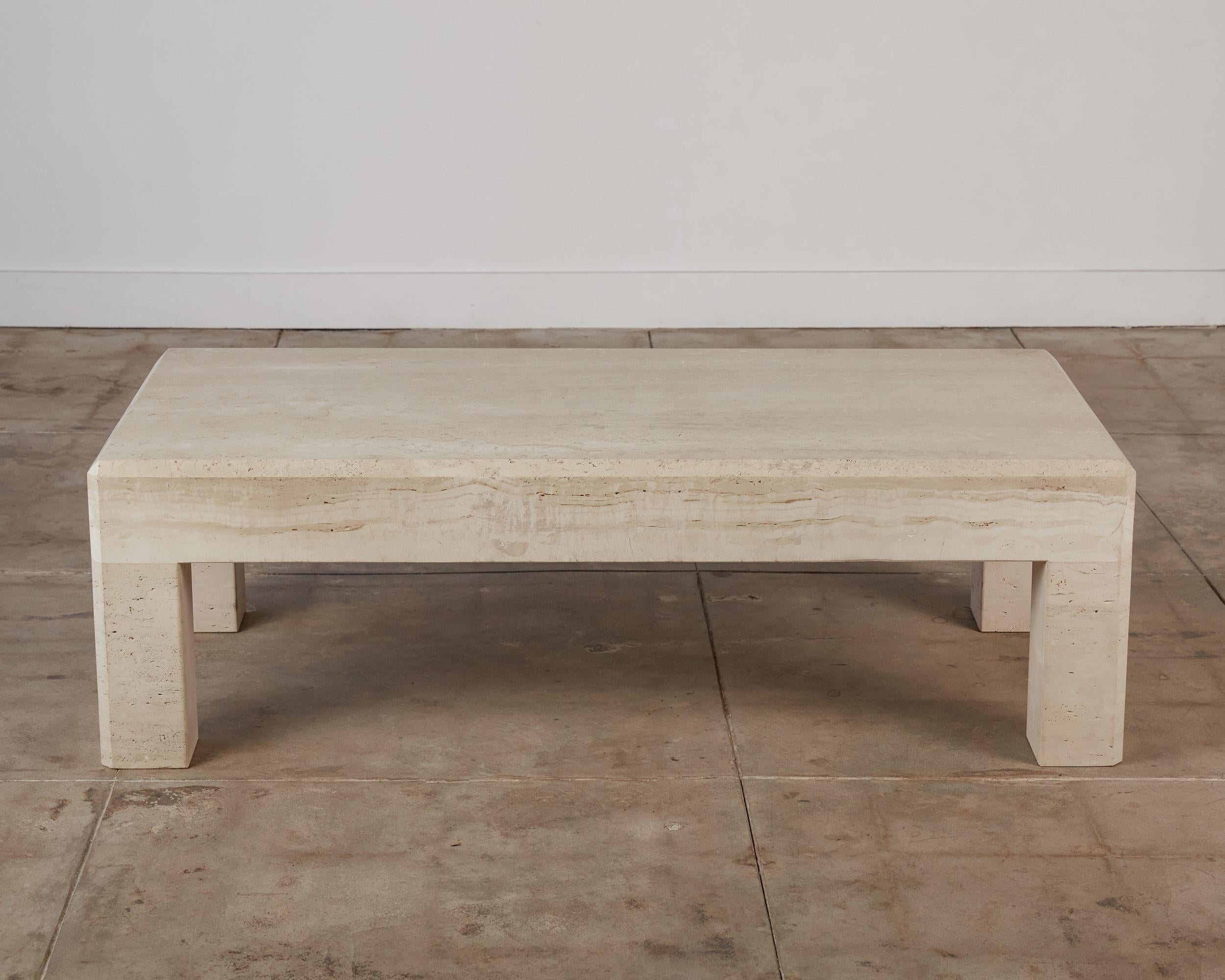 Postmodern travertine coffee table, Italy, c.1980s. This rectangular table has a thick travertine top, that sits atop four square column legs, featuring a chamfered edge detail. With a sleek shape that is reminiscent of tables designed by Italian