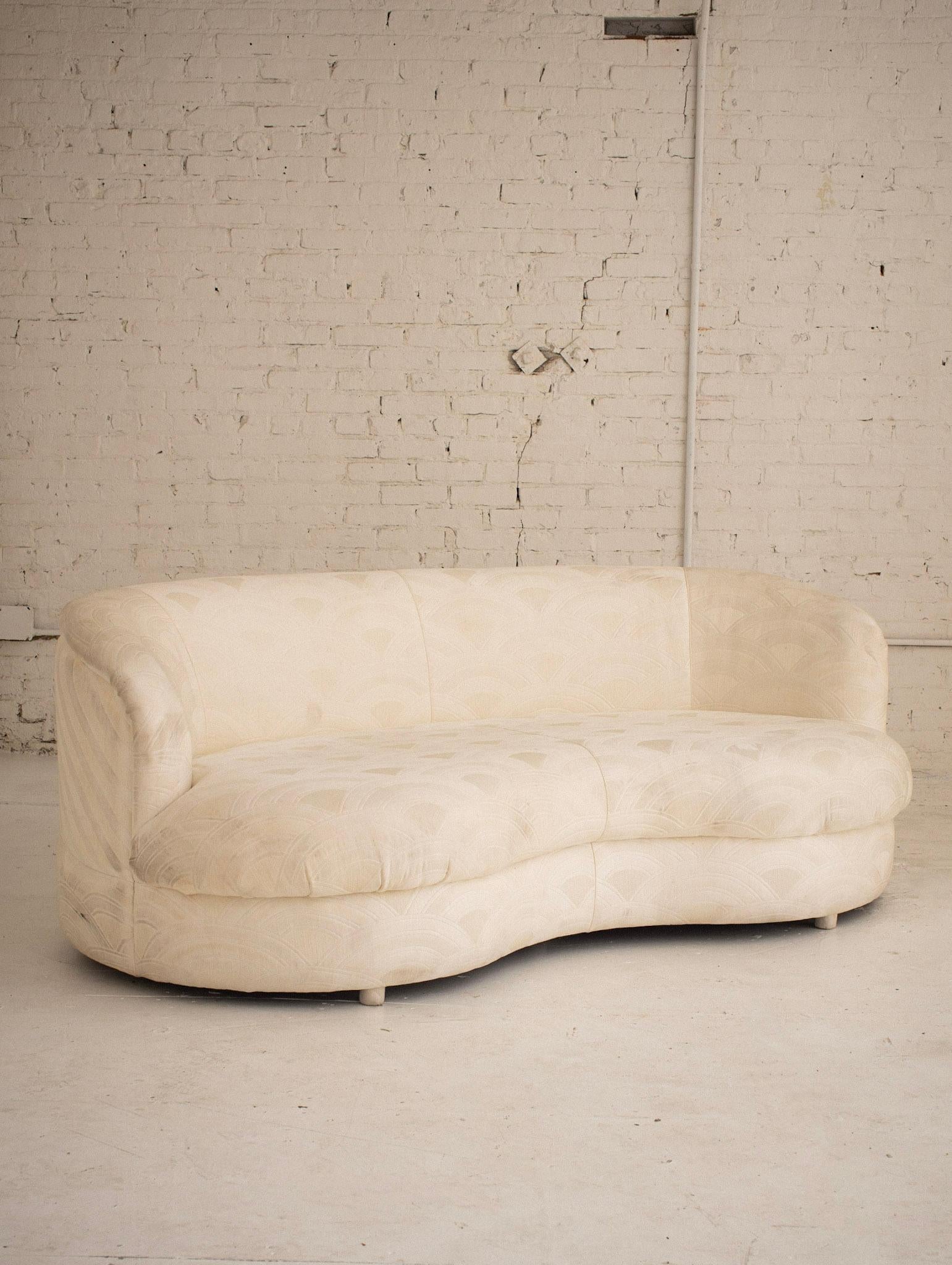 A postmodern cloud form sofa. Kidney silhouette. A deeper seat depth, ideal for lounging. Original cream upholstery with quilted detail. Reupholstery recommended. Pair available, sold separately.