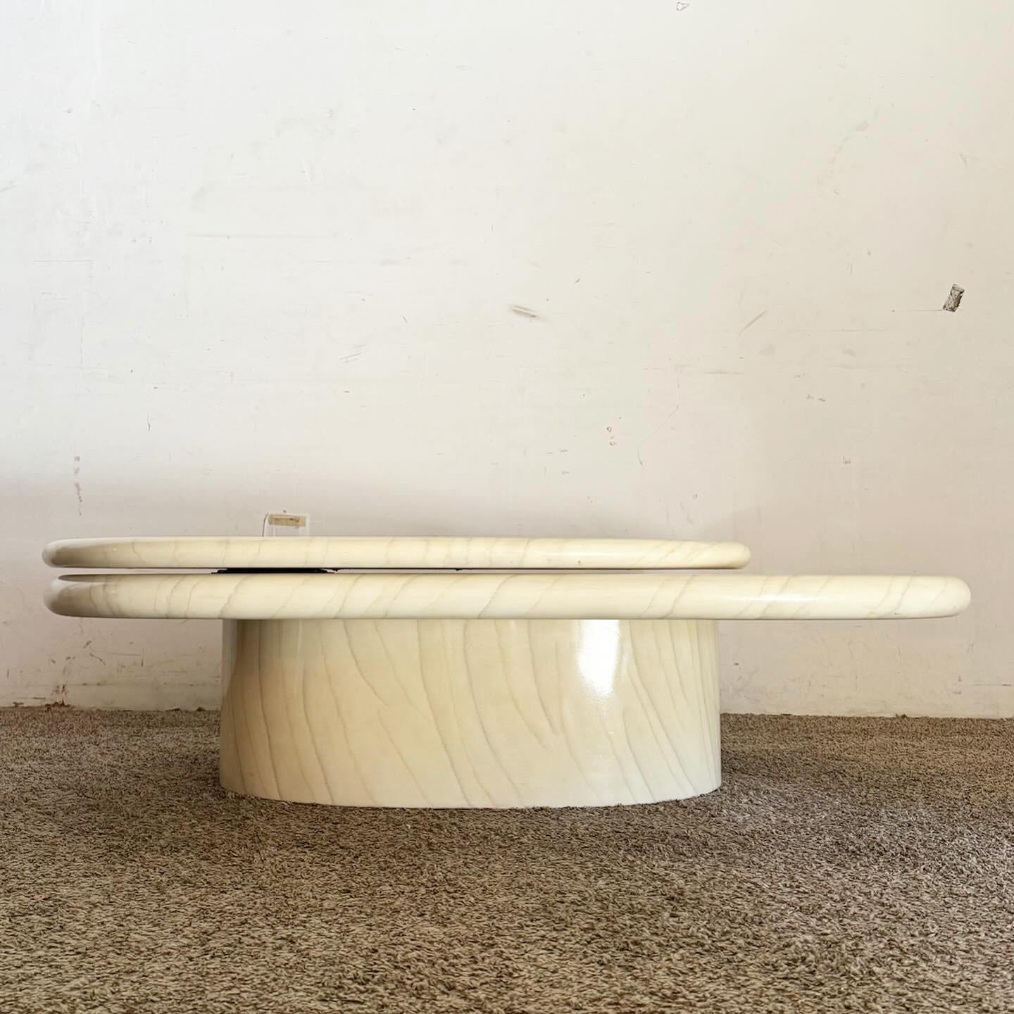 Révolutionnez votre espace de vie avec la table basse ovale à plateau pivotant en fausse pierre laquée postmoderne. Cette table présente un design unique de plateau pivotant à deux niveaux, offrant à la fois style et fonctionnalité. La finition