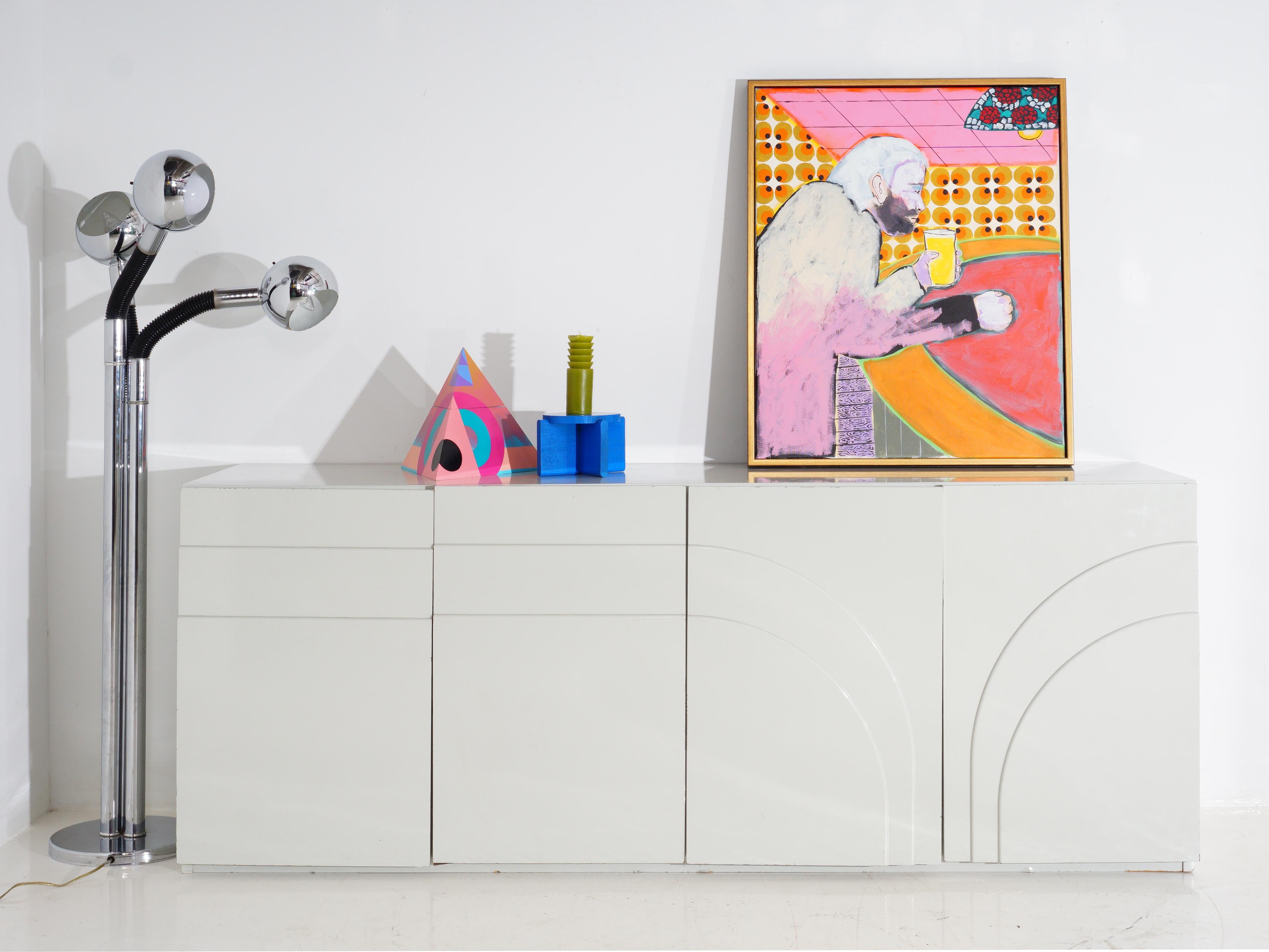 This 1980s postmodern lacquered sideboard is more than just a piece of furniture; it's an artful rebellion against blandness. With its bold lines and glossy finish, it's the punk rocker of storage solutions, refusing to conform to the ordinary. This