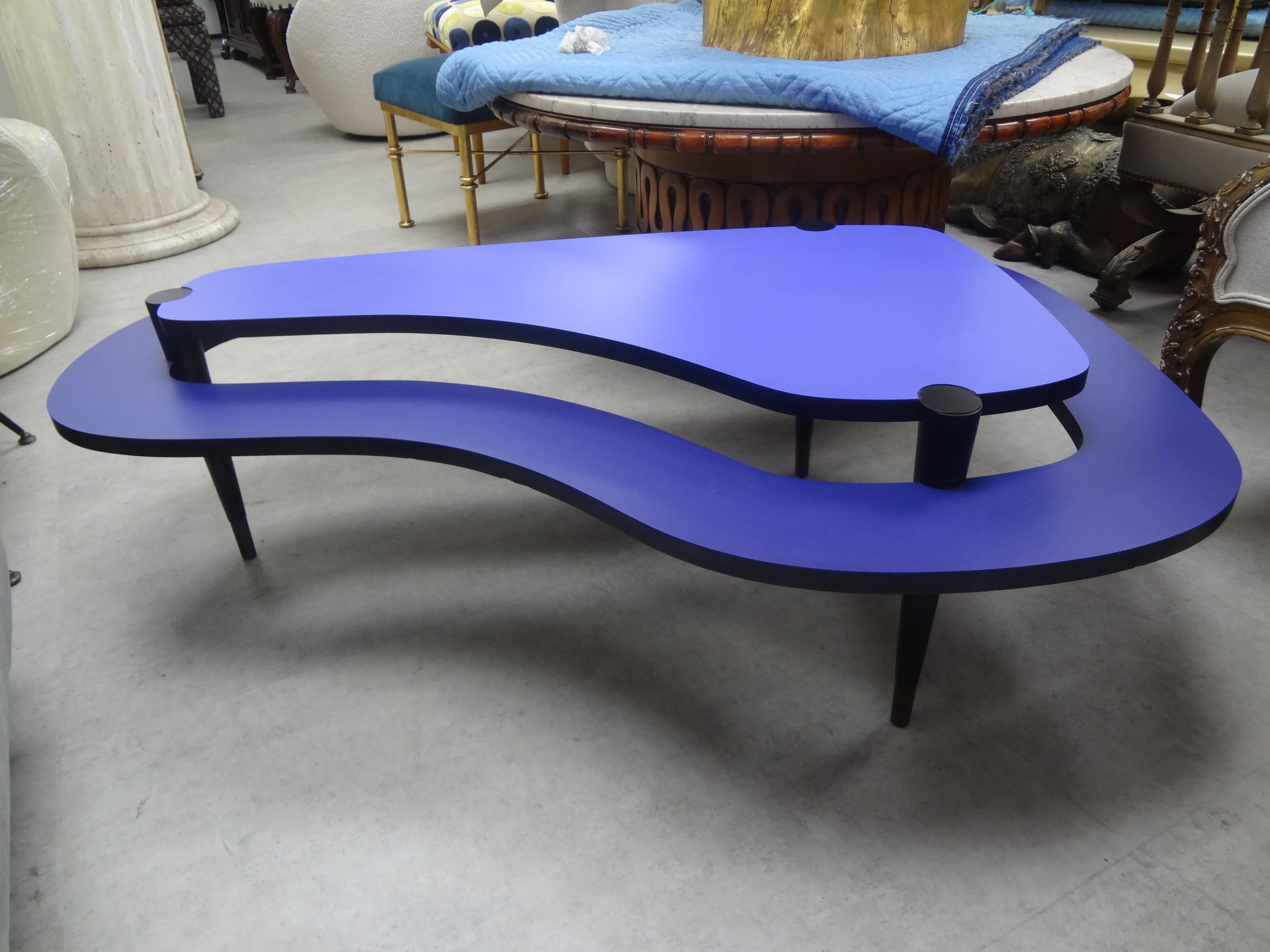 Postmodern laminated two tiered kidney shaped coffee table. This stunning post modern laminate cocktail table or coffee table was executed in fantastic purple and lavender shades with tapered legs and brass sabots.