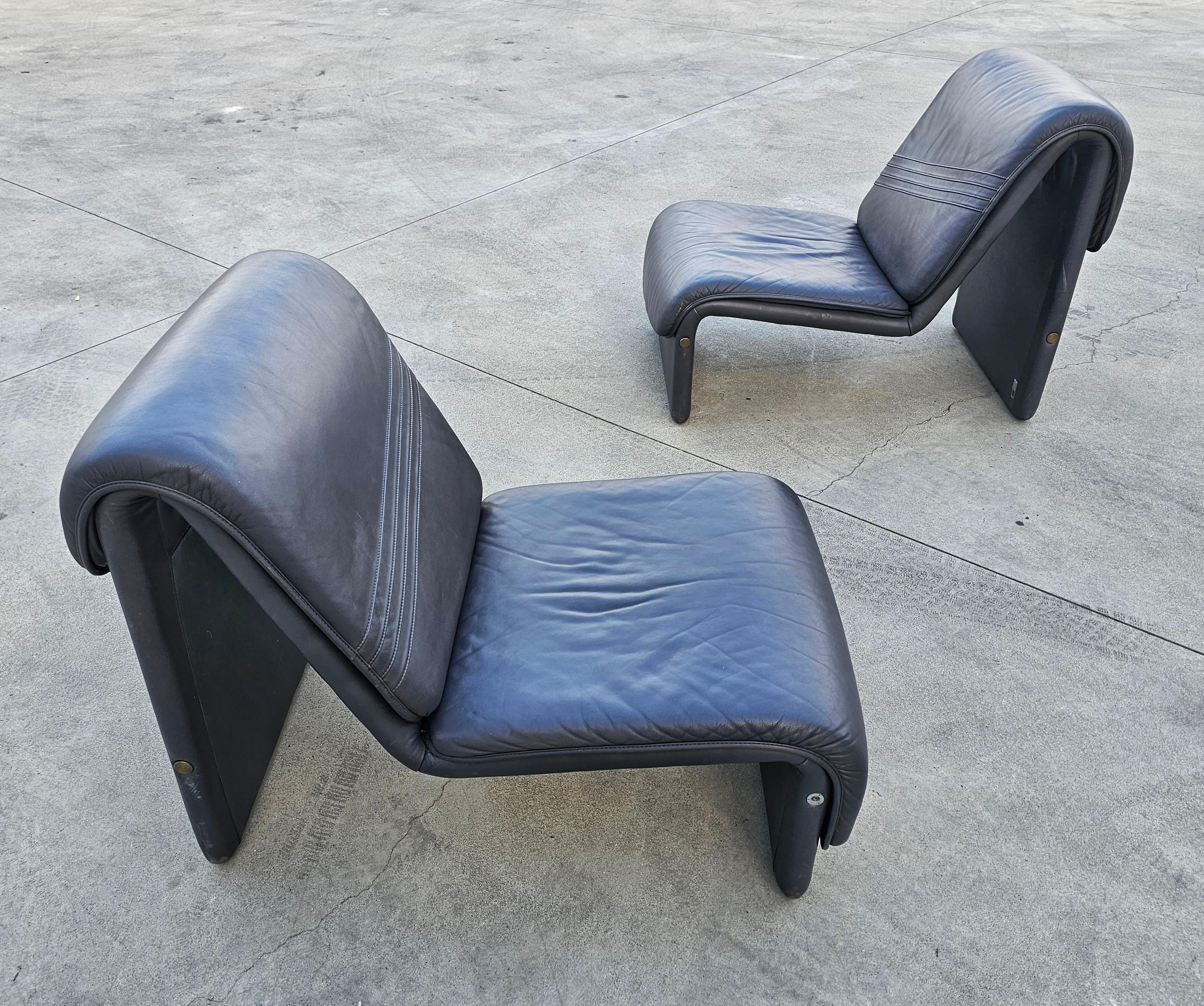 In this listing you will find a pair of postmodern lounge chairs made in Etienne Fermigier style, featuring minimal profile and attractive curved aesthetic. These chairs were manufactured by Swiss Seats, with manufacturer's plates still attached to