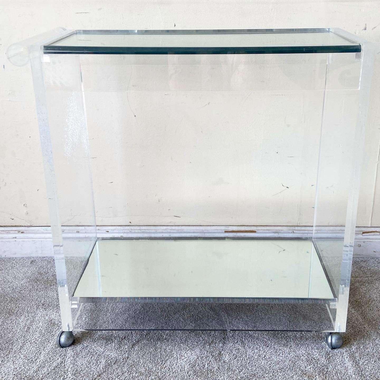 Stunning postmodern lucite bar cart. Features a cylindrical handle with a thick glass top and mirrored bottom shelf.