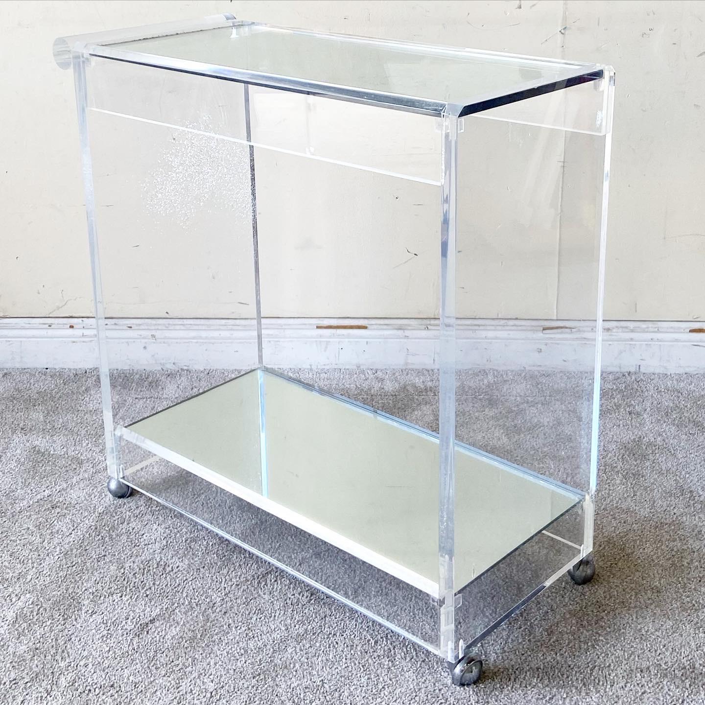 Stunning postmodern lucite bar cart. Features a cylindrical handle with a thick glass top and mirrored bottom shelf.
 
