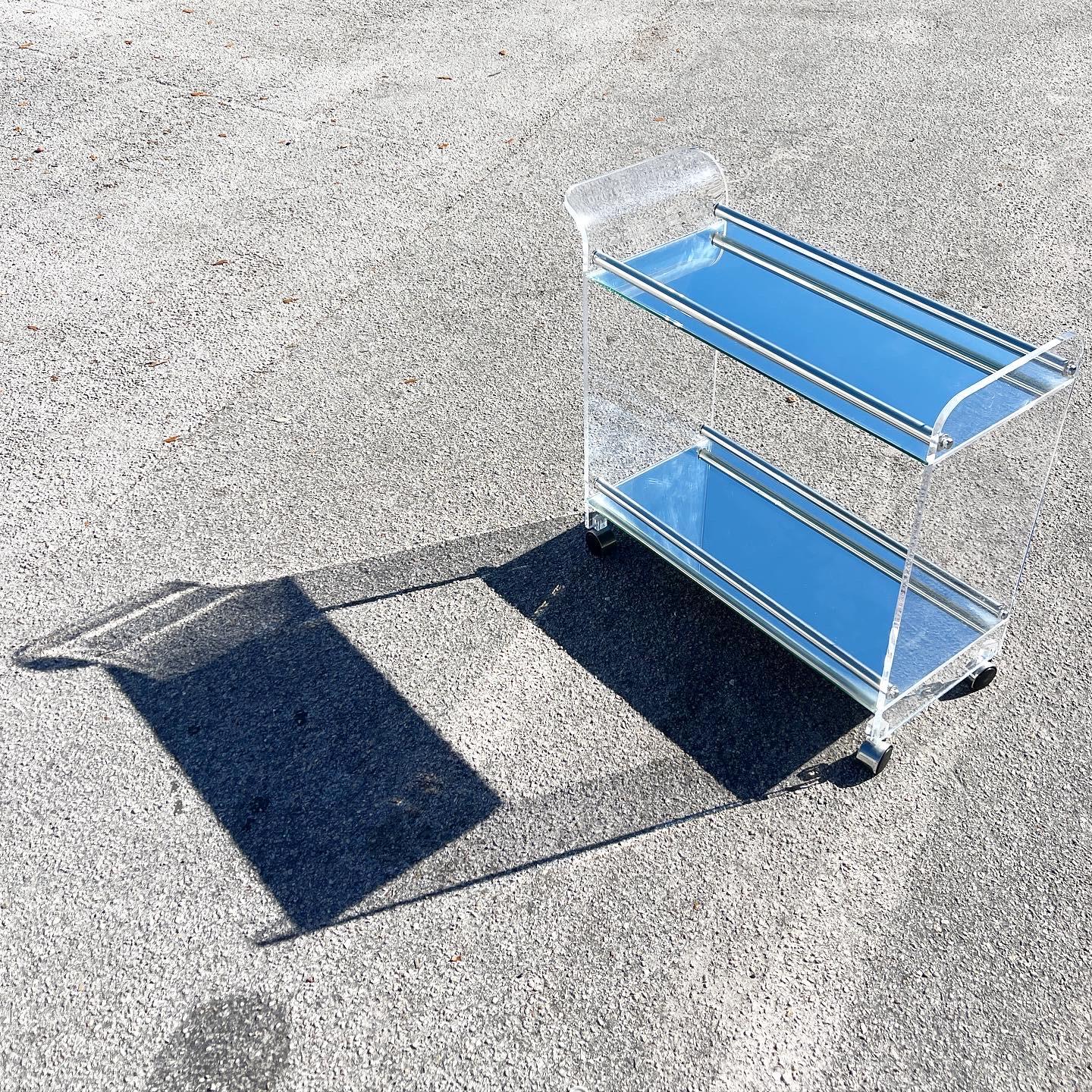 Stunning lucite bar cart. Features two mirrored shelves with tubular lucite arms.