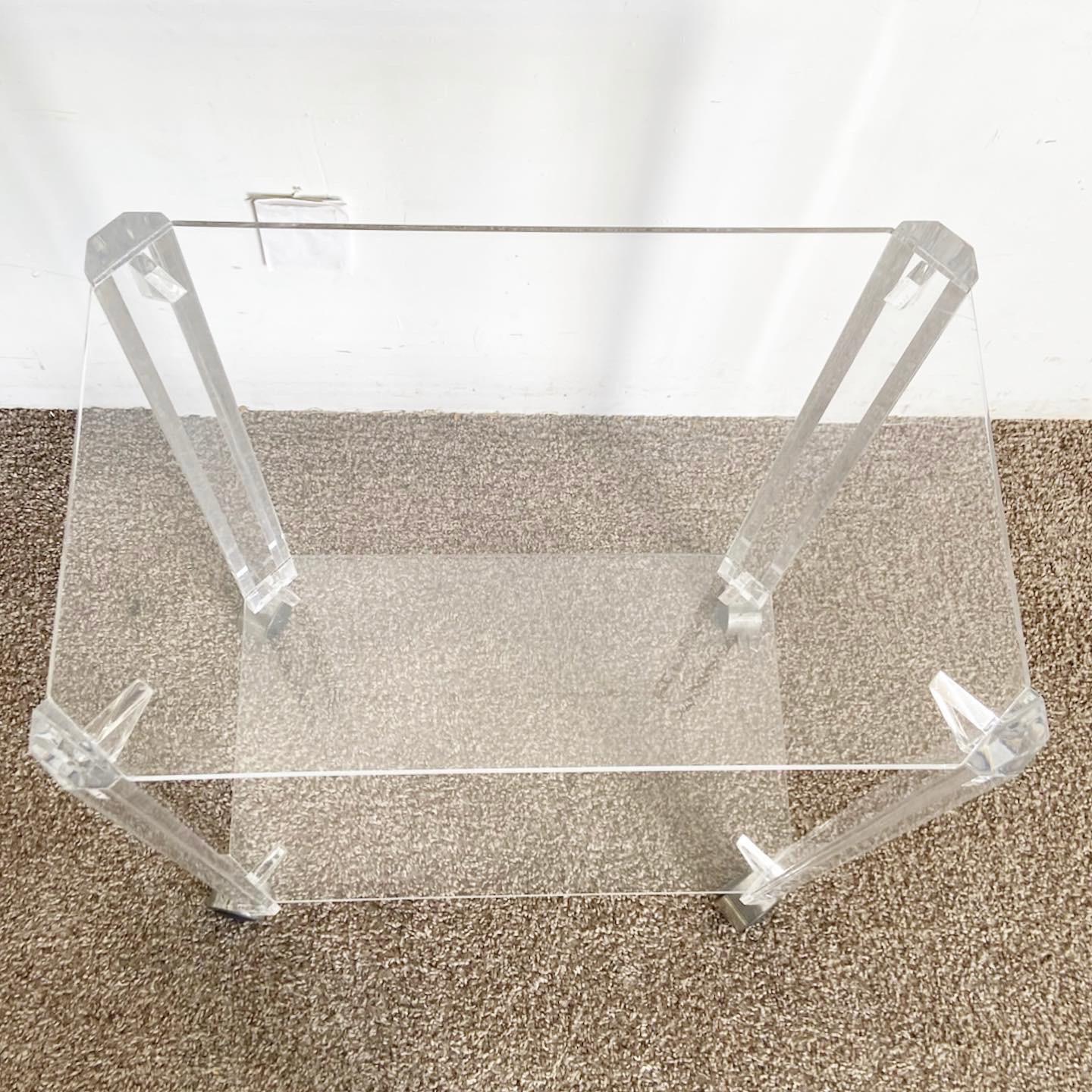 Embrace the world of postmodern design with our Lucite Two Tier Bar Cart on Casters. This piece showcases a sleek, transparent Lucite structure, providing ample space for storage and display. Its smooth casters ensure easy mobility, perfect for