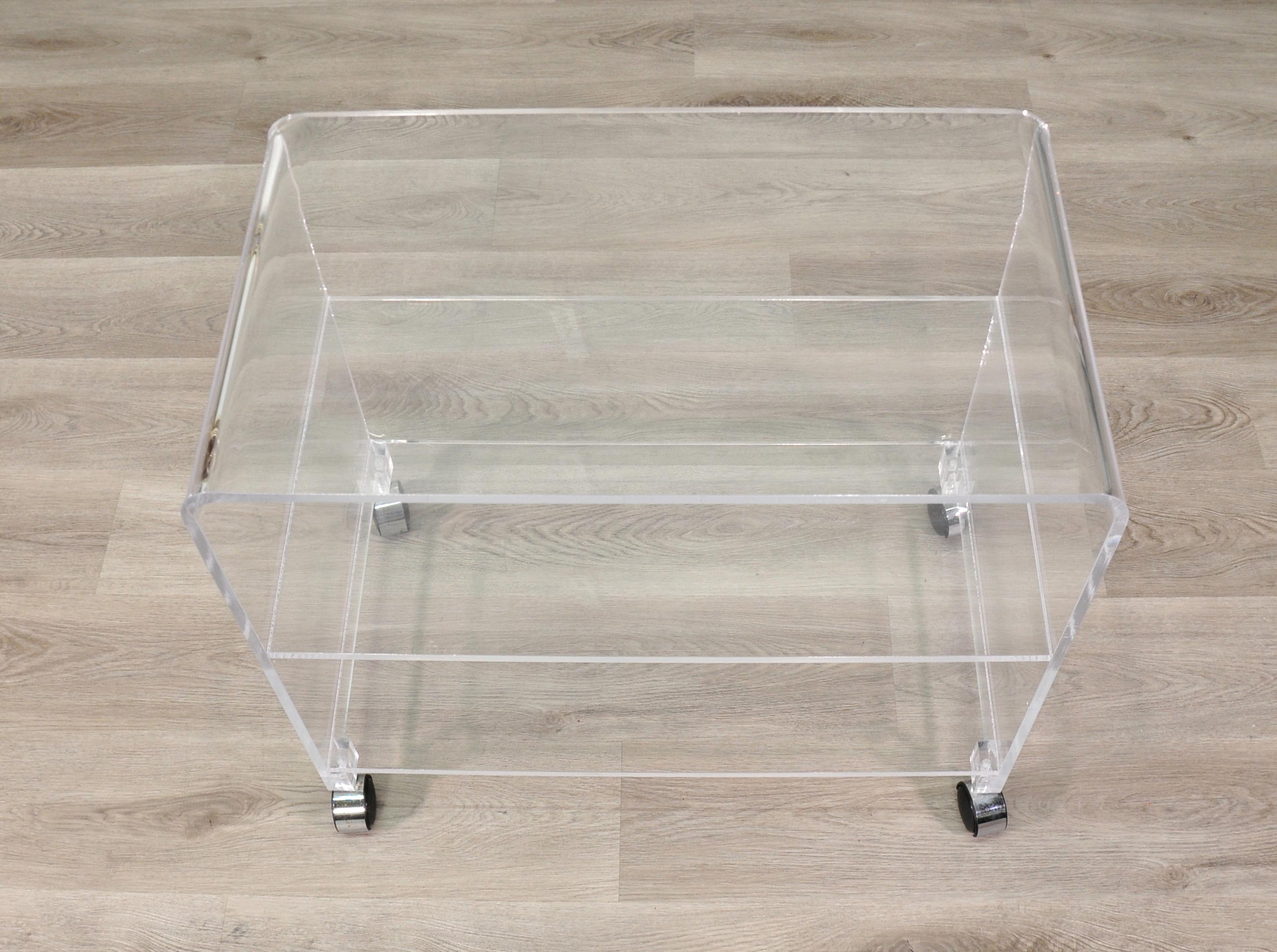 Vintage bar cart or occasional table on wheels, formed of Lucite (clear acrylic) on four easy pull chromed wheels. Waterfall three-tier design with smooth rolling feature. Inquire with Select Modern about local delivery options.