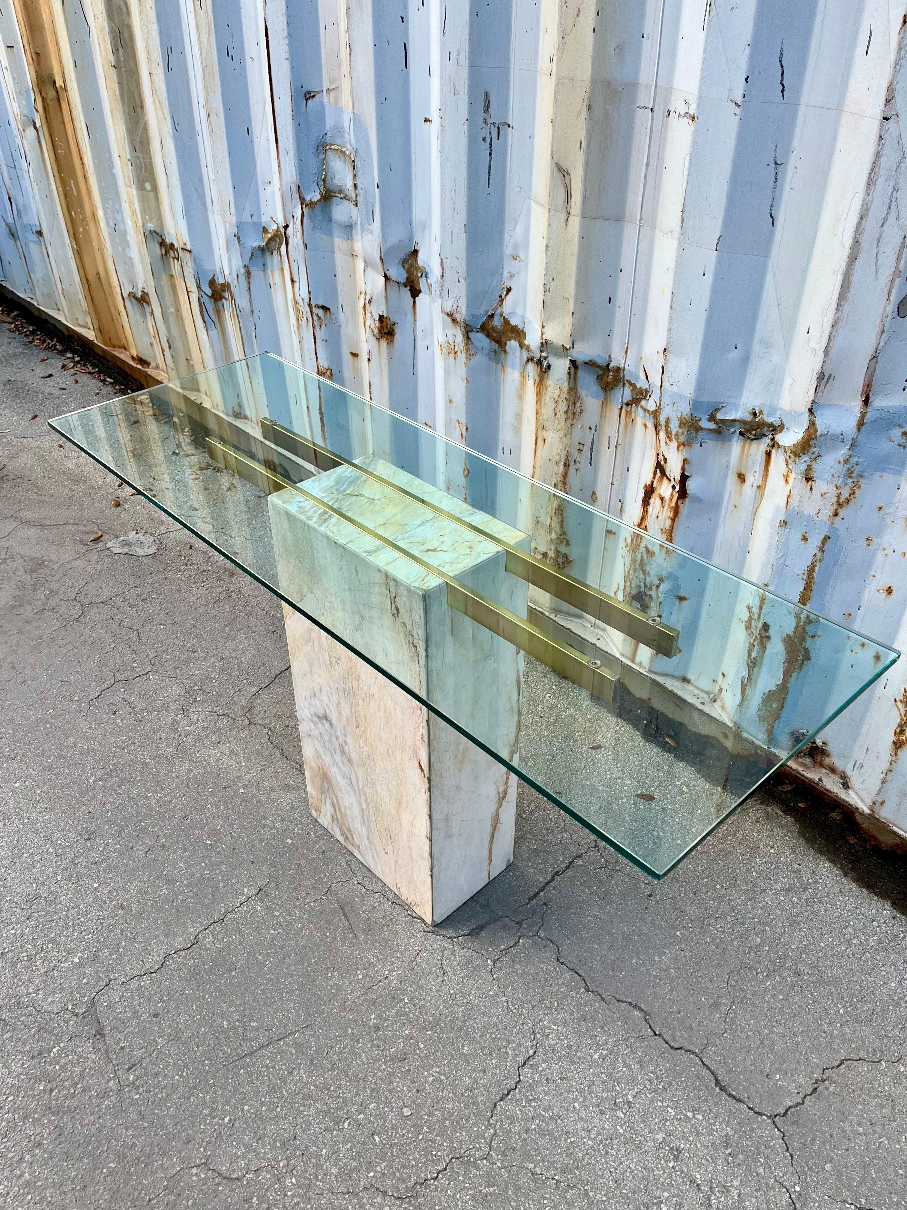 Postmodern Marble and Brass Console / Entry Table in the Artedi Style. Circa 1980s.
Features a minimalist design with a marble base with beautiful stone veins, polished brass glass supports and a thick removable glass top.
In excellent original