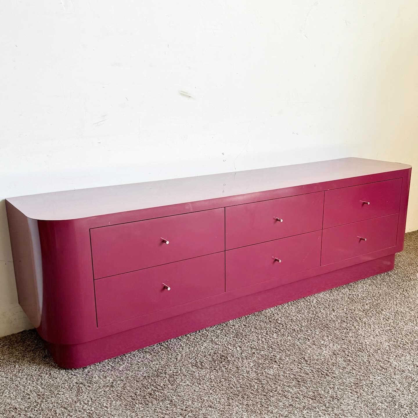 Embrace the boldness of the Postmodern era with the Maroon Lacquer Laminate Lowboy Dresser. This vibrant piece captivates with its dynamic purple hue, embodying the era's audacious spirit.
 
 Its low profile and clean lines are accentuated by the