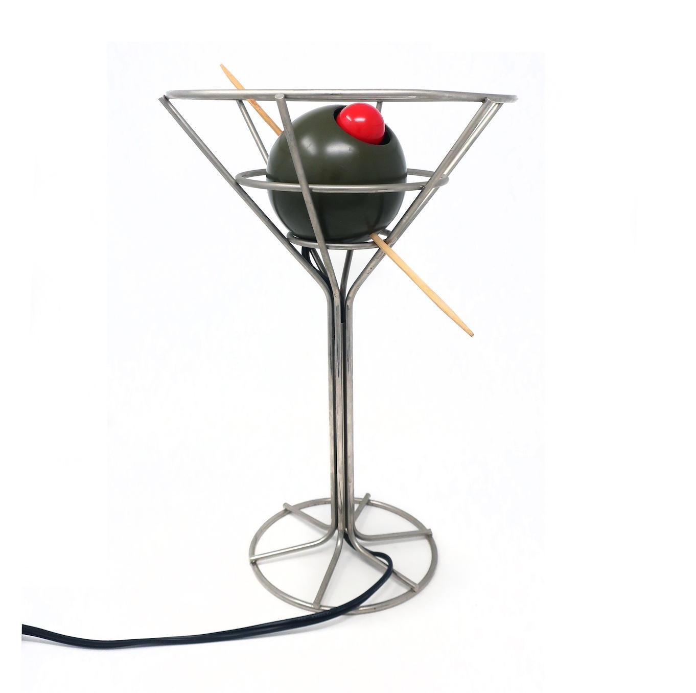 Rare lampe martini postmoderne de 1993 conçue par David Krys. Un fil métallique forme la forme du verre avec une olive verte embrochée, farcie d'une ampoule rouge déguisée en piment. Idéal pour les amateurs de pop art, d'articles de bar, de martinis