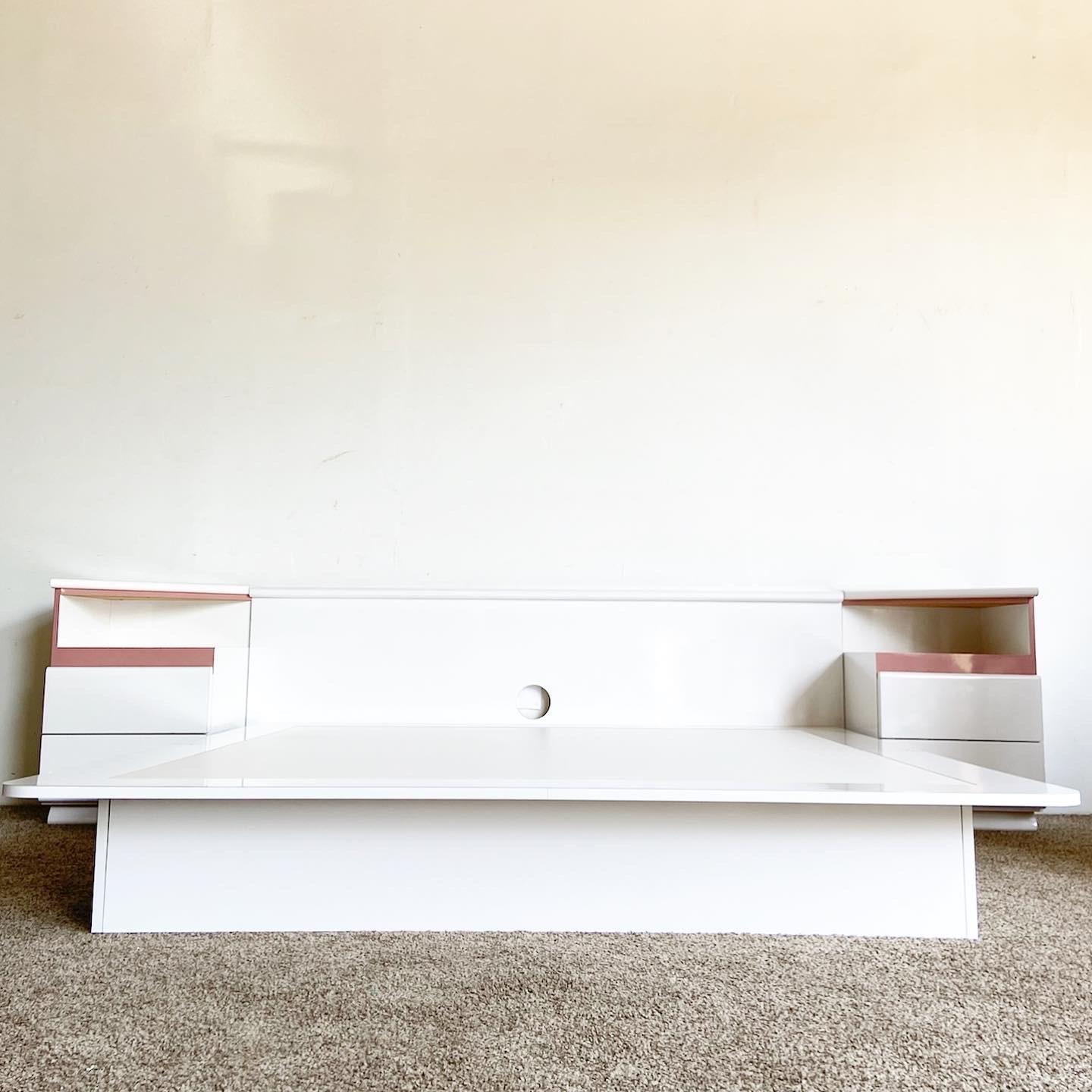 Exceptional vintage king size postmodern platform bed with triangular top nightstands. Features a white lacquer laminate with mauve pink accents.

Platform bed measures 76”W, 80.25”D, 11”H
Nightstands measure 19”W, 19.5”D, 29”H
Headboard