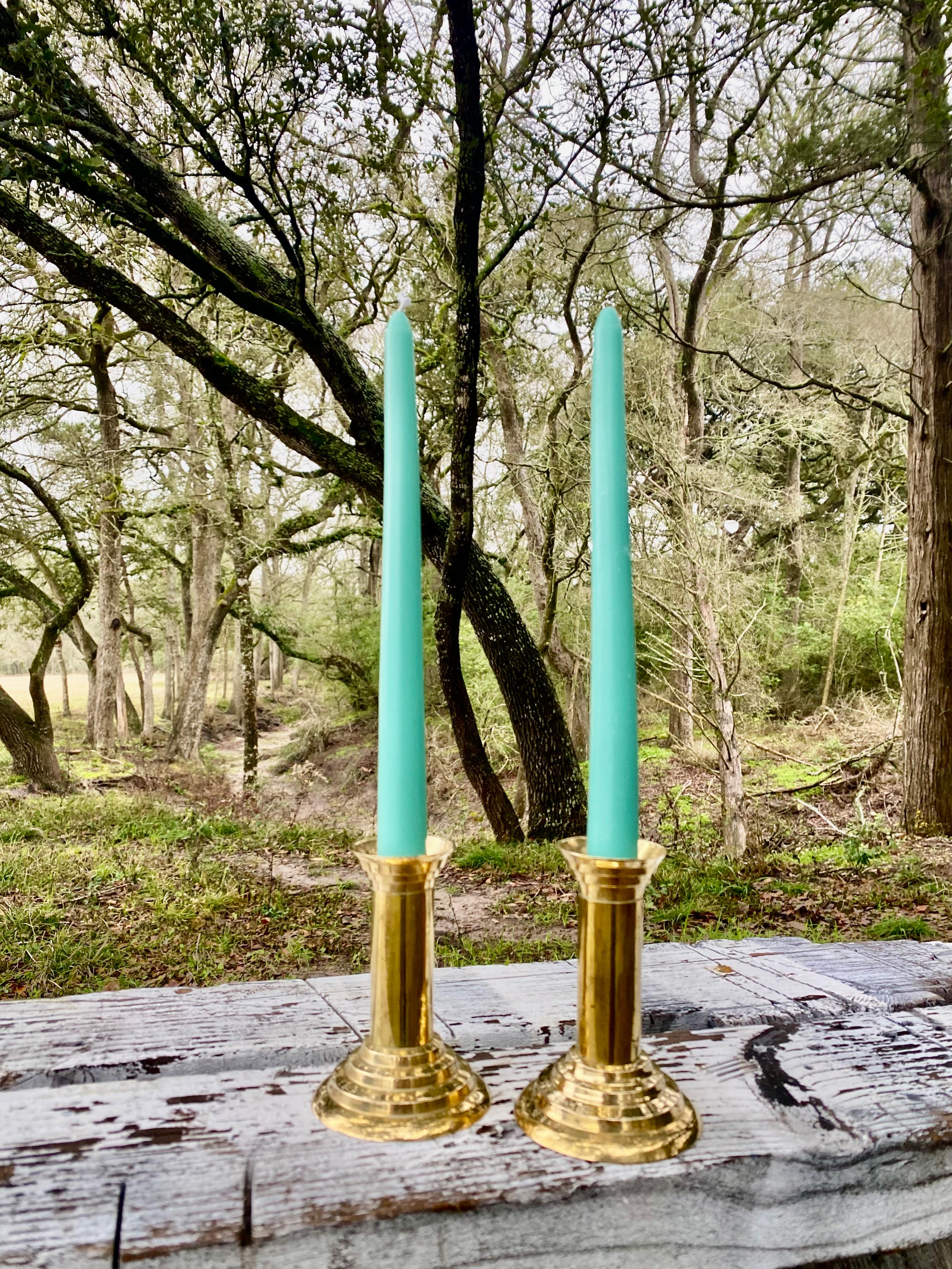Ce duo exceptionnel de bougeoirs en laiton illustre la fusion raffinée de l'élégance néoclassique et de la forme minimaliste. Les bases élégantes en laiton poli ancrent le design, tandis que les cônes aqua apportent une touche de couleur inattendue