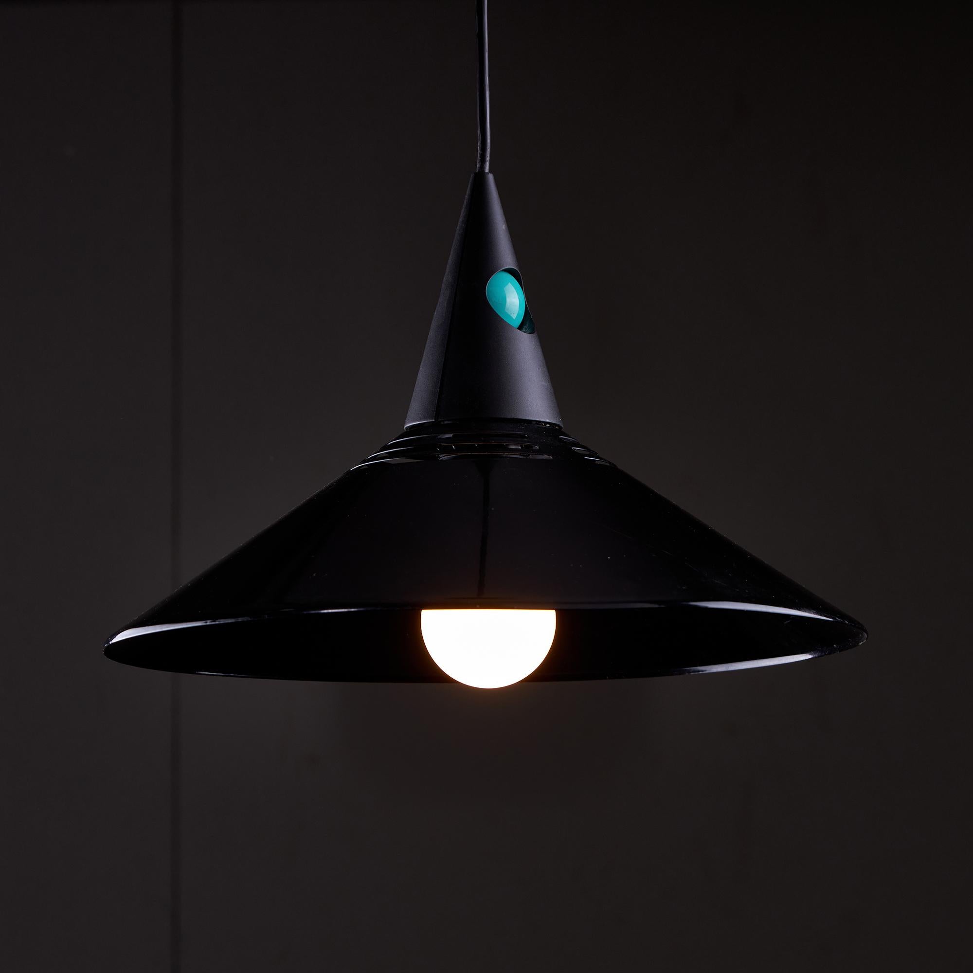 This piece is a 1980s postmodern black Italian Memphis style metal pendant. It features a cone-shaped plastic top that serves as the main component of the pendant. The Italian Memphis style is characterized by bold geometric patterns, vibrant