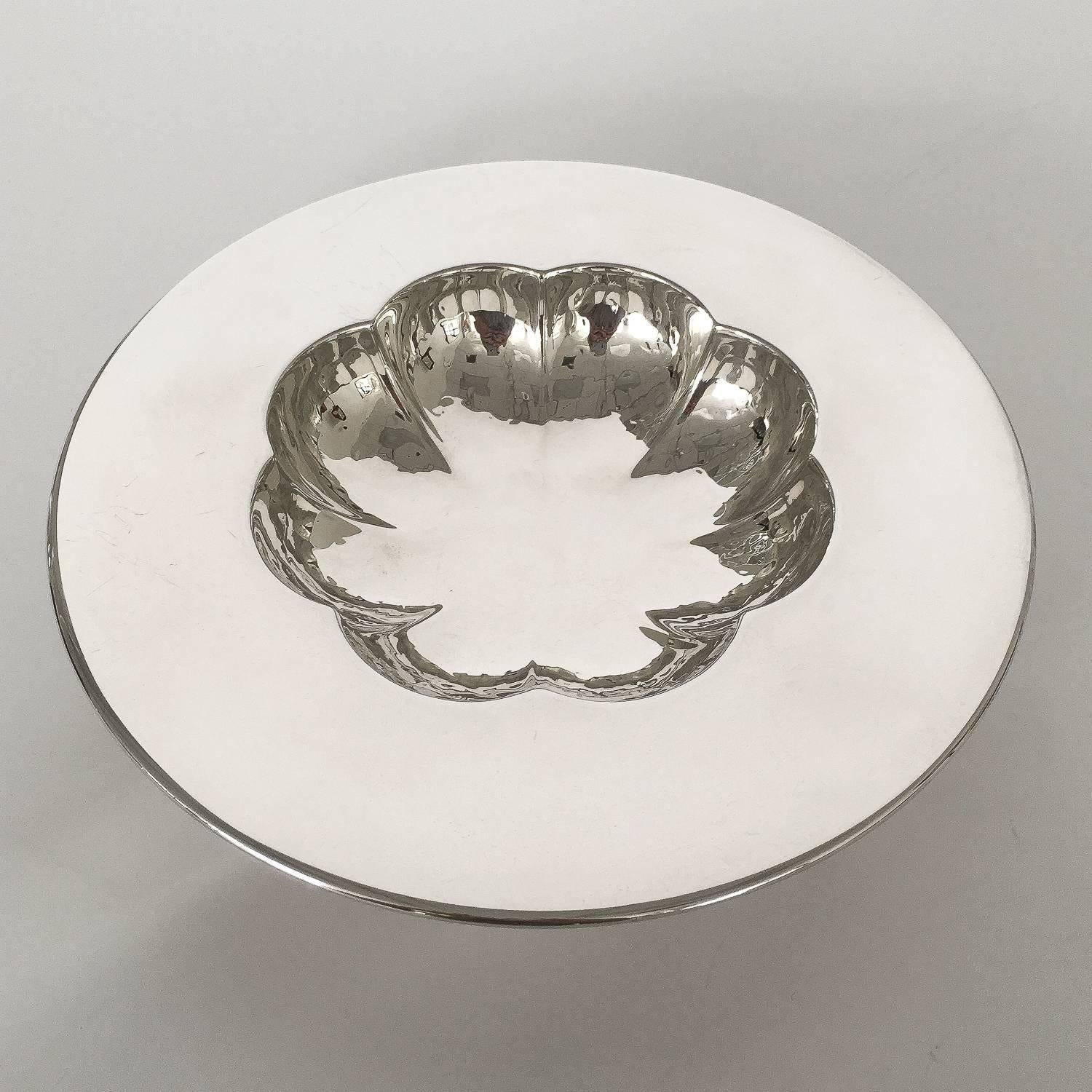 Michael Graves (1934-2015) silver plate bowl / candy dish for Swid Powell, circa 1989. This round bowl features a wide flat rim with a scalloped interior bowl with peen-hammered finish and sits on a fixed cruciform base. Signed and dated on the