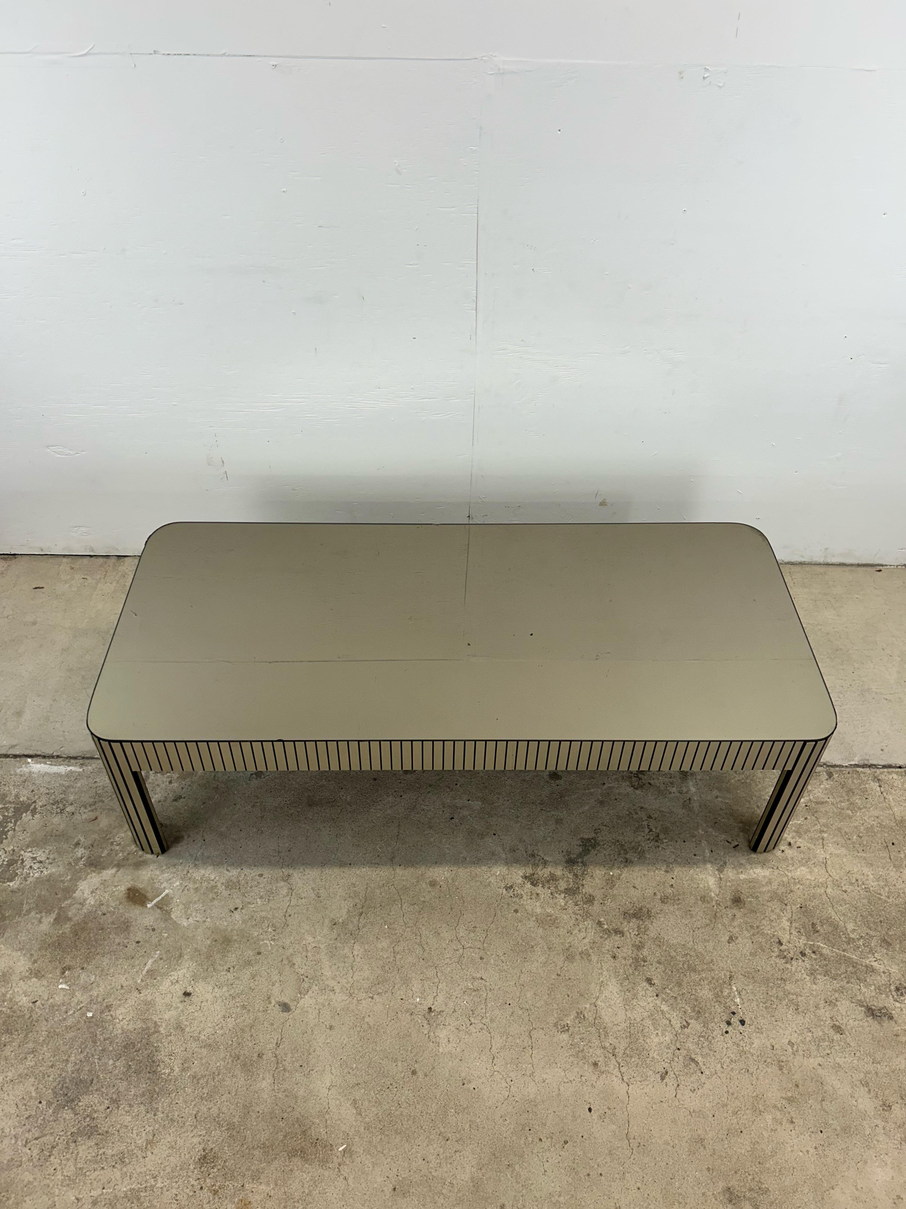 Cette table basse postmoderne est dotée de pieds et d'une base chromés et d'un plateau en verre miroir. u2028u2028La table d'appoint assortie est disponible séparément.
u2028Dimensions : 54w 24d 15.75h 

Condition : La base chromée présente quelques