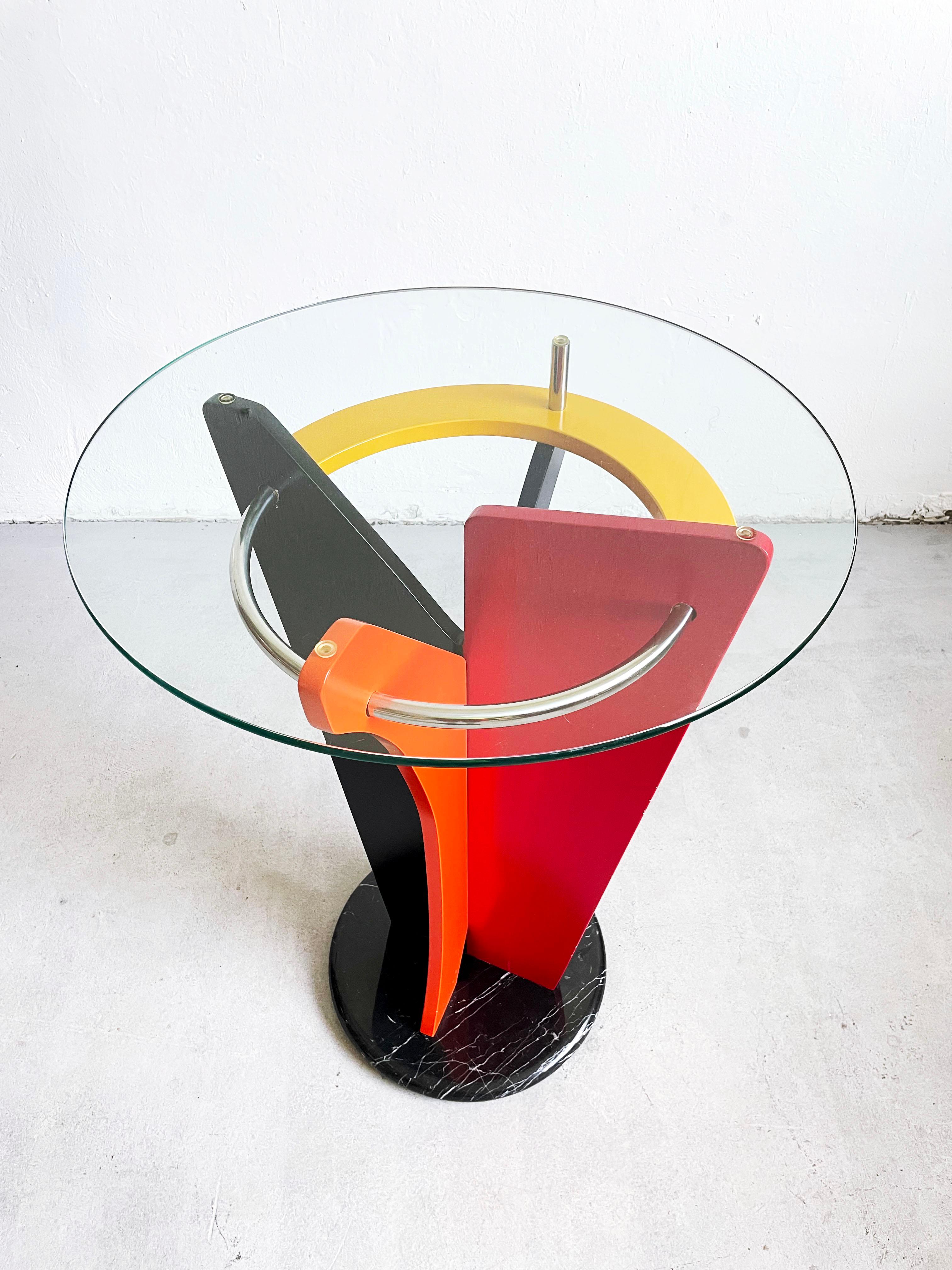 1980's Postmodern Peter Shire Style Italian Pedestal or Bar Table.

This beautiful sculptural Memphis design statement piece features abstract wooden structure in yellow, red, black, orange and blue color finish
The round base of the table is made