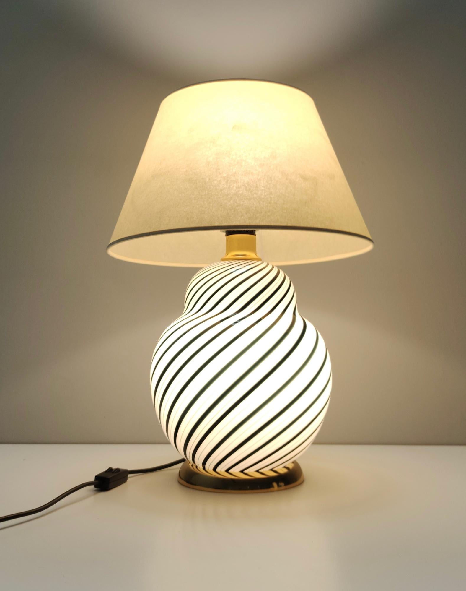 Fabriqué en Italie, années 1980. 
Elle est réalisée en verre de Murano noir et blanc, en laiton et en tissu.
Cette lampe à poser comporte deux lumières : elles peuvent être allumées séparément ou en même temps. 
Cette lampe peut présenter de légères
