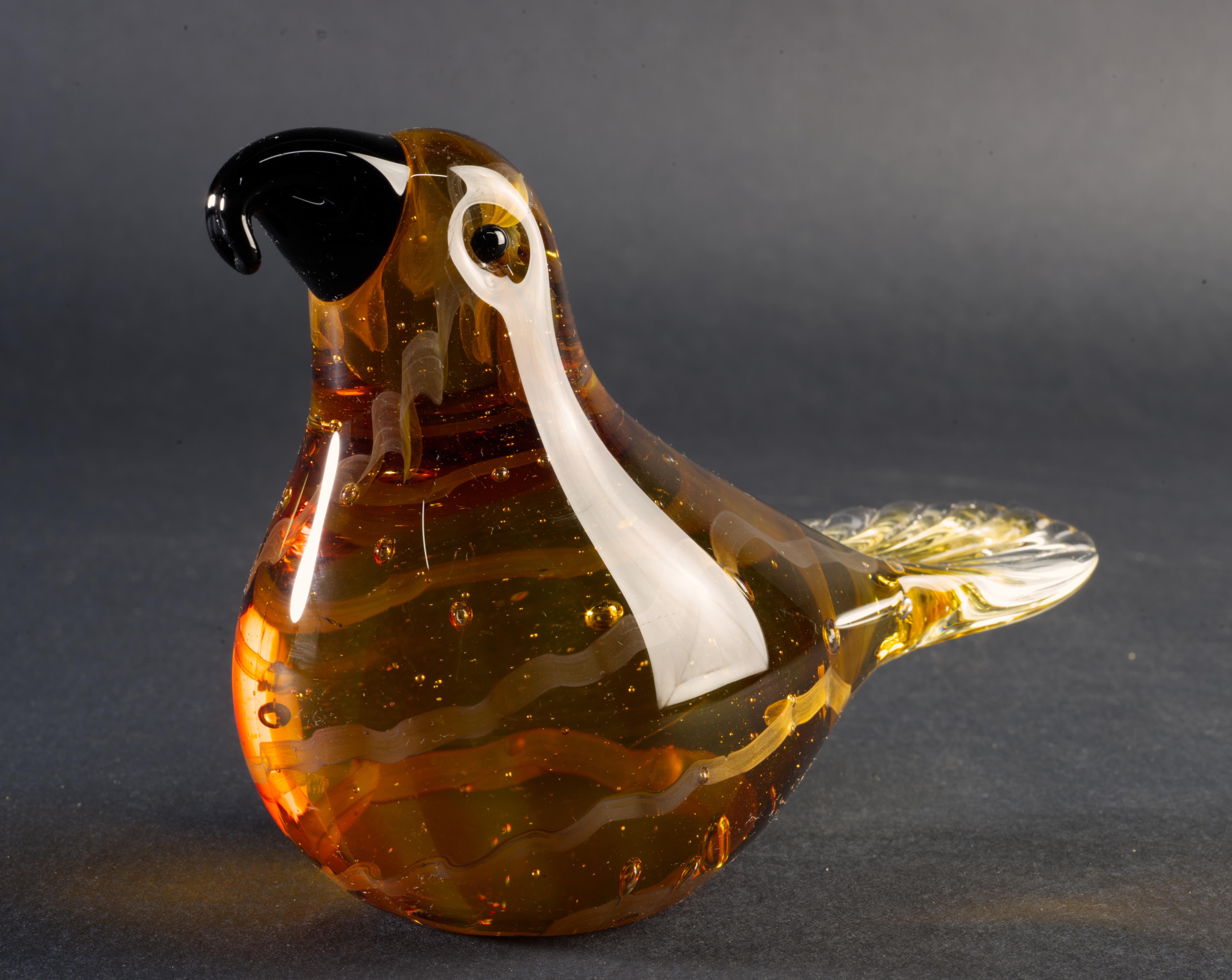   Playful bird figurine or paperweight is made in sommerso technique; amber colored glass gather with swirls of light-colored glass ribbons is cased over with clear glass. Controlled bubbles are used to give the piece depth and movement, accenting