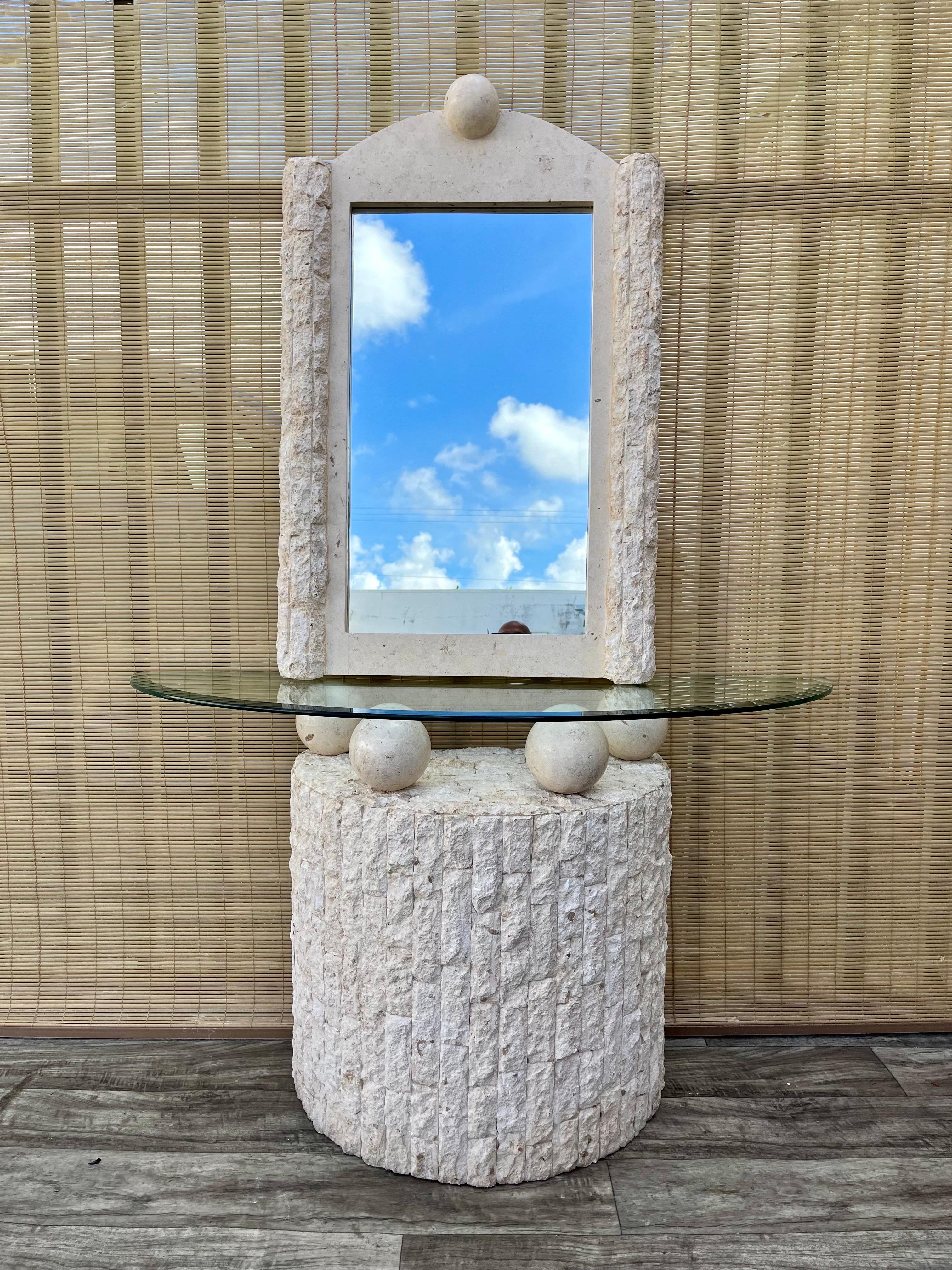 Vintage Postmodern Natural Mactan Stone Entry Console Table With Wall Mirror. C 1990s 

Features a half-moon fractured Mactan Stone facade with a removable glass top resting on four smooth, tessellated orbs, and a matching ornate ready-to-hang wall