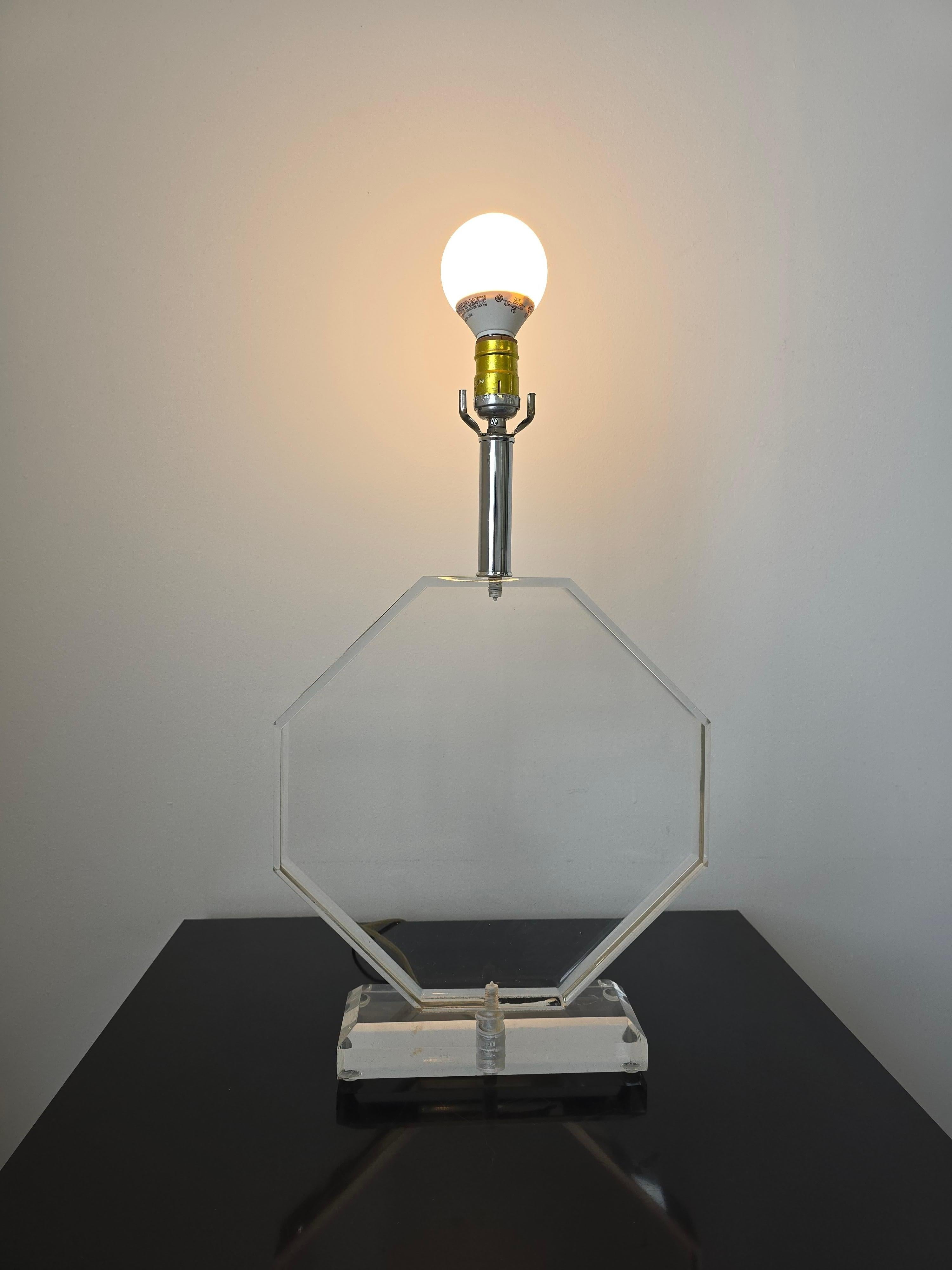 Post Modern lucite base octagonal table lamp. This stunning lucite table lamp is octagonal shaped which gives it a modern touch making it a perfect accent lamp for various styles of decor. Its made in solid lucite and bares weight to it. 
Overall