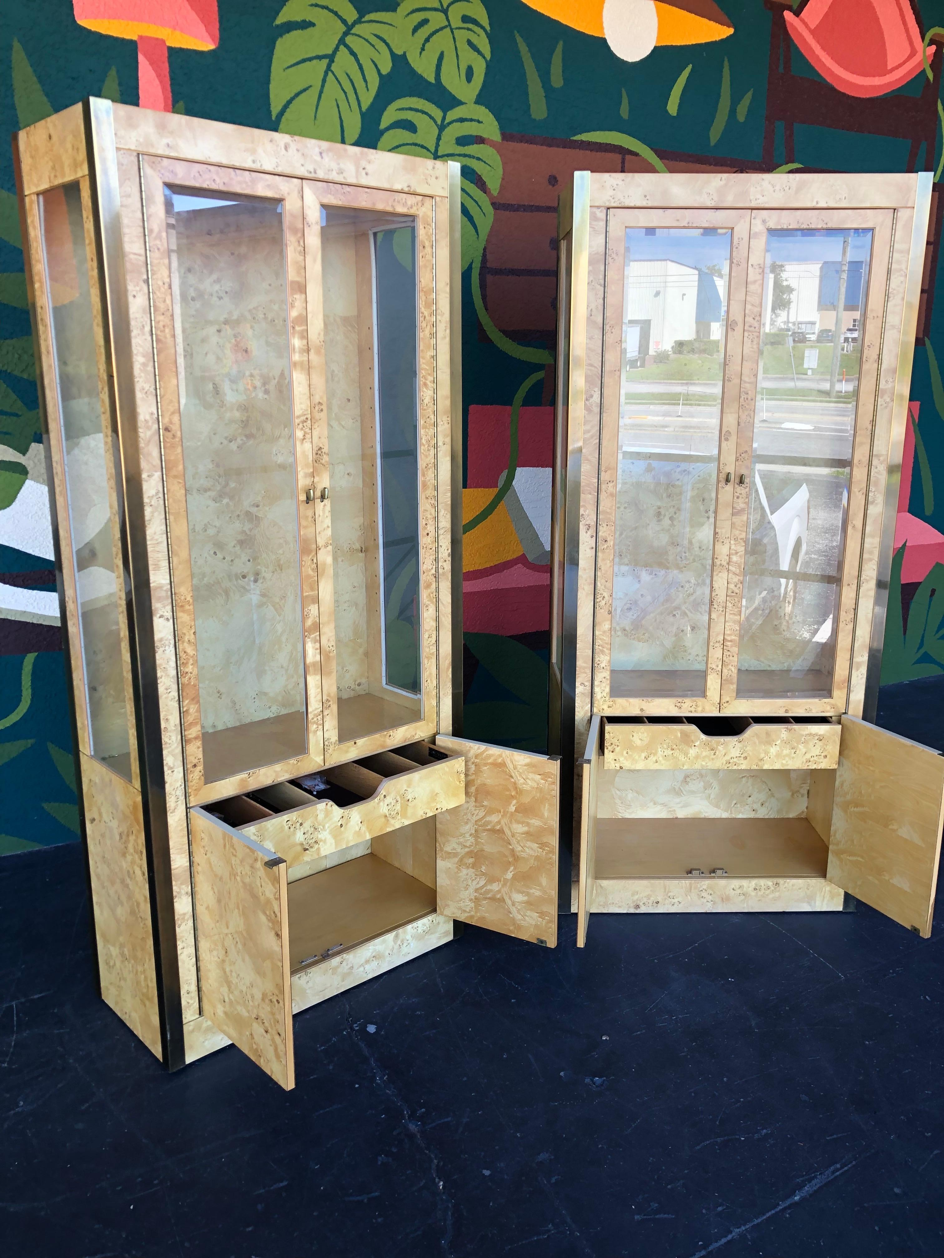 Mid Century/Post Modern 1970’s Tomlinson Olive Burlwood Display Cabinet Pair. A striking set with brass trim/hardware, glass front doors and side panels, and interior lighting. 

These are extremely well made and in excellent original vintage