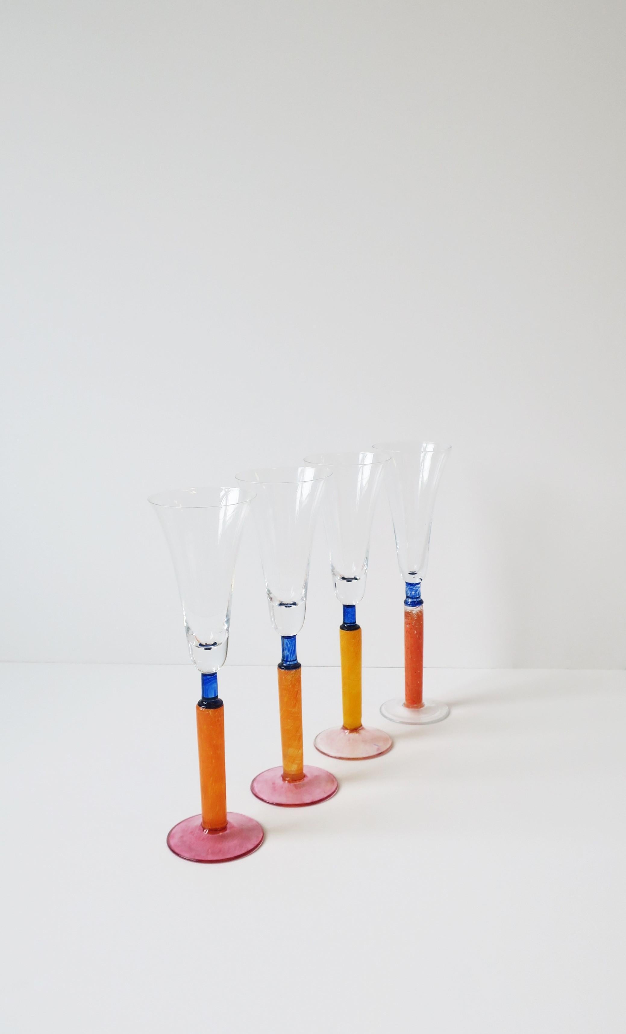 A beautiful set of four (4) Postmodern orange art glass Champagne flute glasses, circa 1990s, Europe. In the style of Kosta Boda, Sweden. Colors include orange, pink, and blue. A beautiful set for home, summer, holiday entertaining, and for any bar,