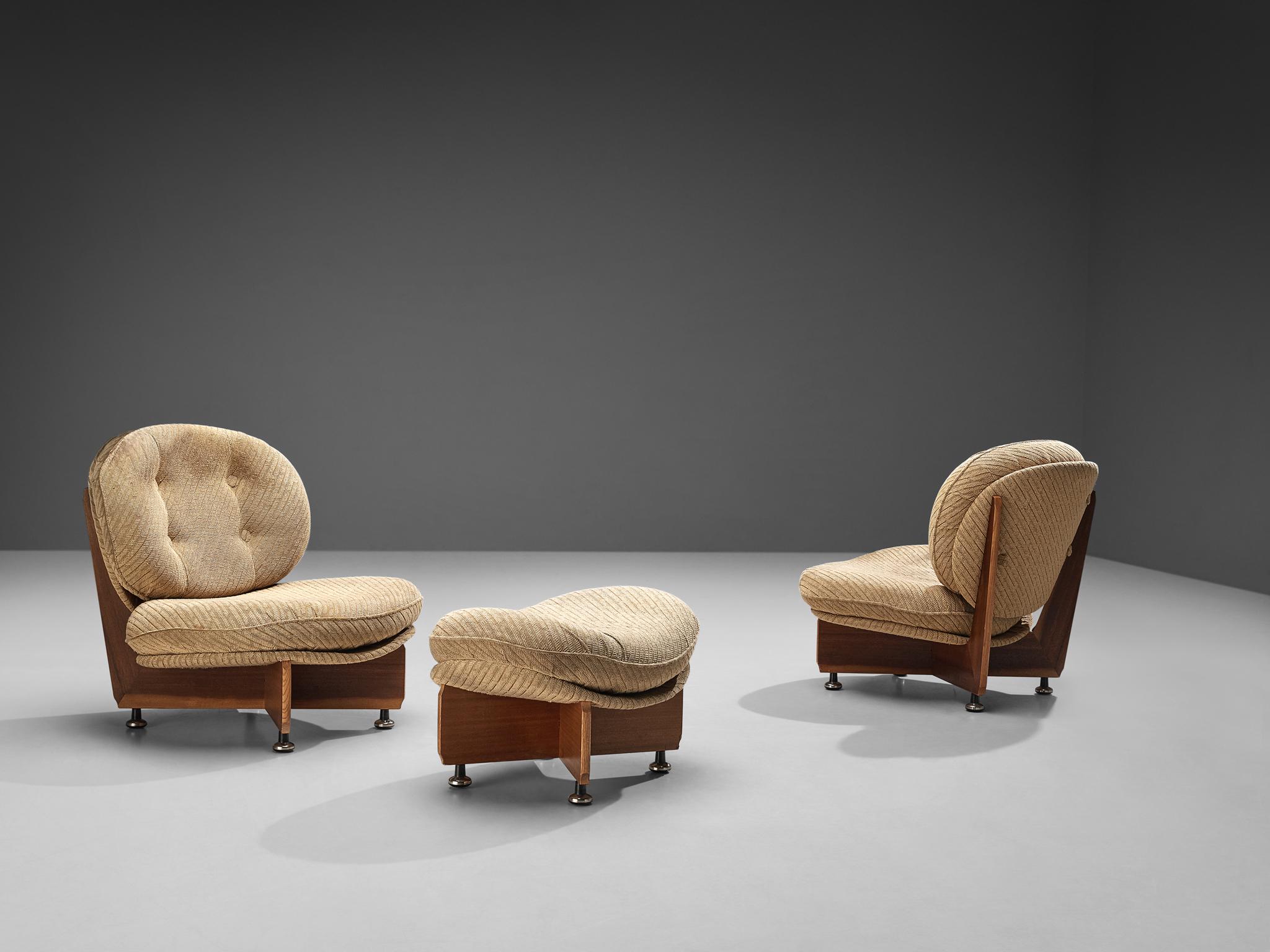 Pair of lounge chairs with ottoman, beige fabric, mahogany, Europe, 1970s.

These whimsical chairs are characterized by a unique construction. The seating area consists of curved shells that hold the voluminous, round cushions. The base convinces