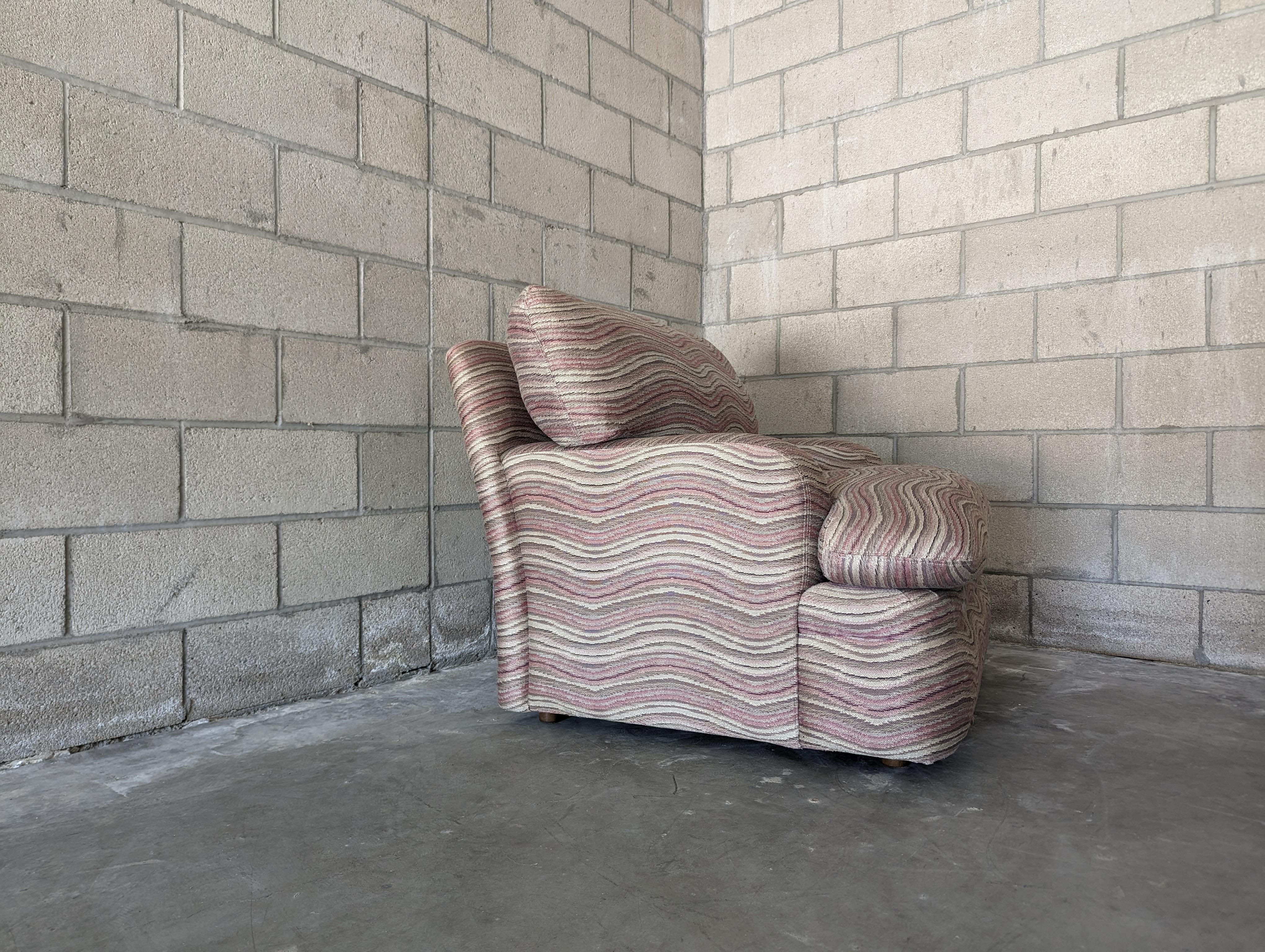 Ce fauteuil postmoderne au design distinctif, datant des années 1980, est une incarnation du style et du confort. Il capture magnifiquement l'essence éclectique de l'époque avec sa forme unique et son tissu qui attire l'attention.

La chaise mesure