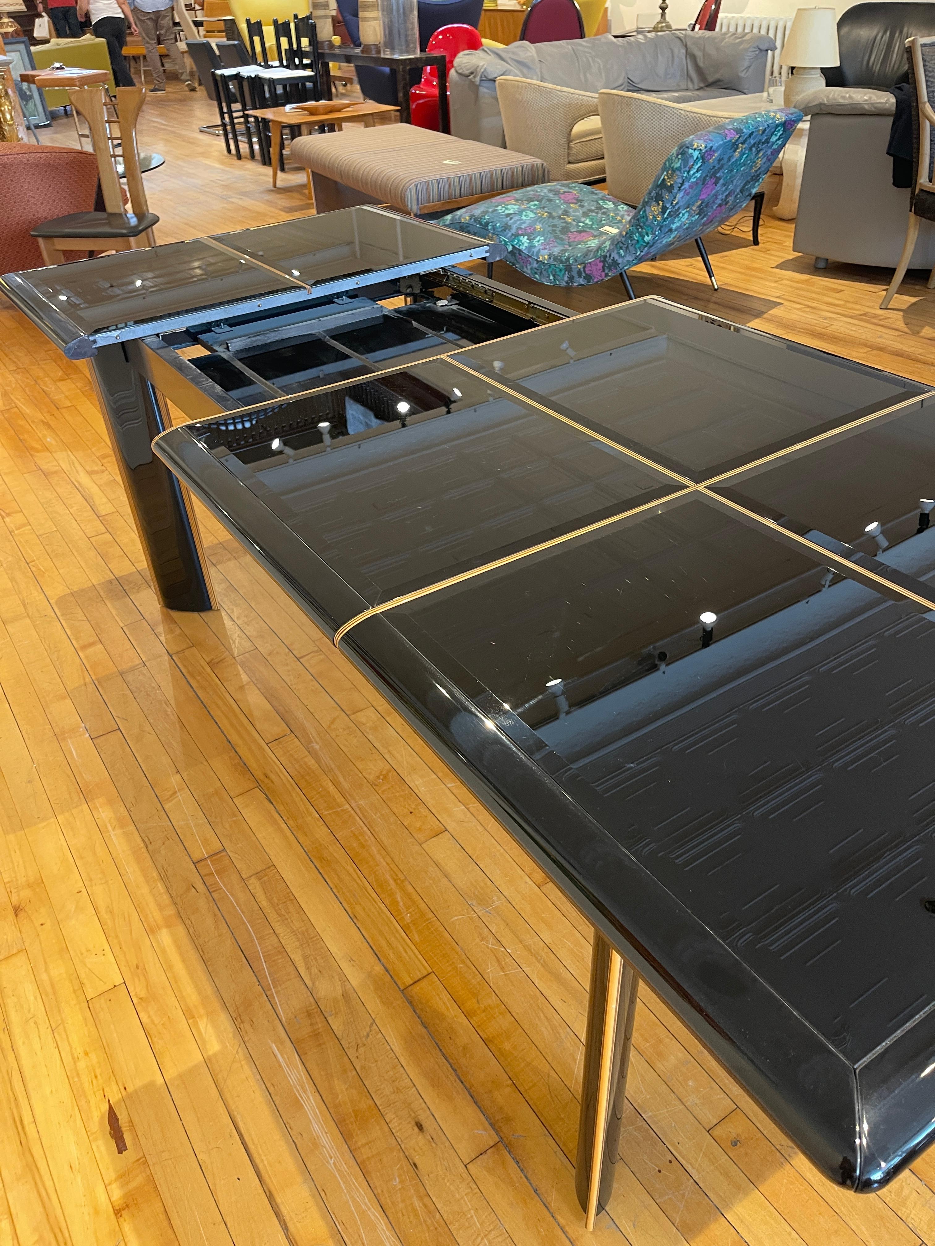Stunning black lacquered and beveled black glass extension dining table. This is an excellent post-modern table said to have been designed by Pierre Cardin. This table was sold by Maurice Villency in the early 1980s. Cinstructed of Lacquered wood
