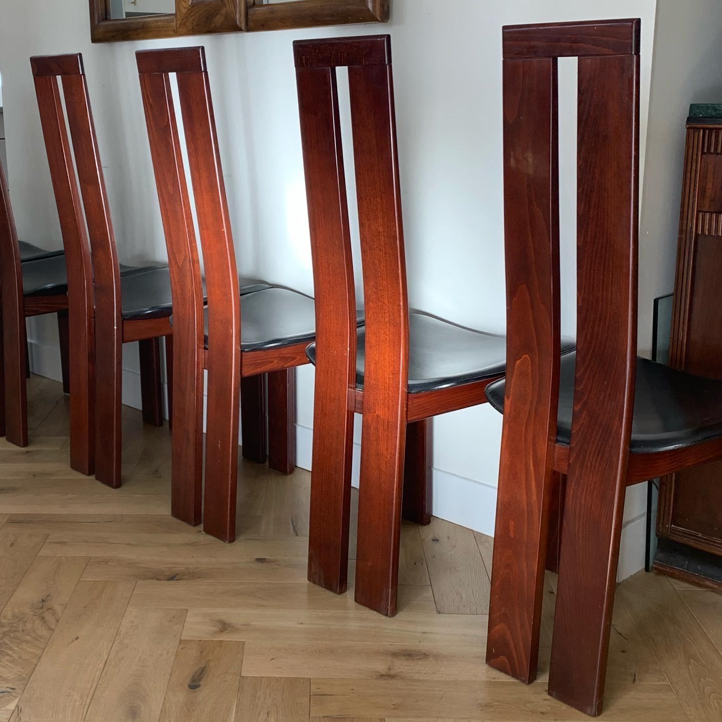 A fabulous set of 6 postmodern dining chairs by Pietro Costantini for Ello Furniture, at once elegant and eccentric. Made in Italy circa mid-1970s. Chairs are a rich cherry wood with original black leather upholstery, and feature the iconic