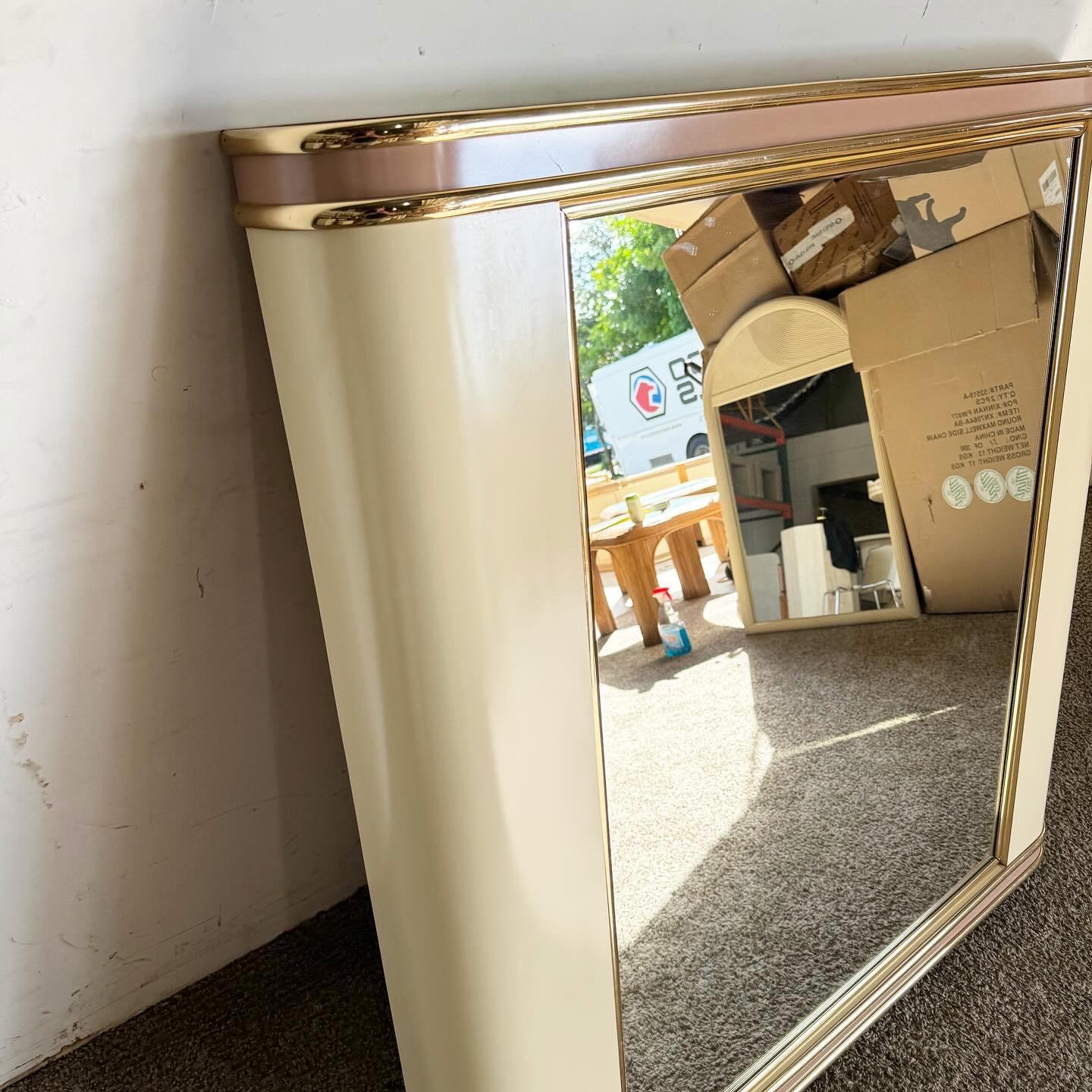 Indulge in the playful sophistication of the Postmodern Pink and Cream Lacquer Laminate Mirror with Gold Trim. This mirror marries soft hues with metallic accents, capturing the exuberant style of the era. It's not just a functional item but a