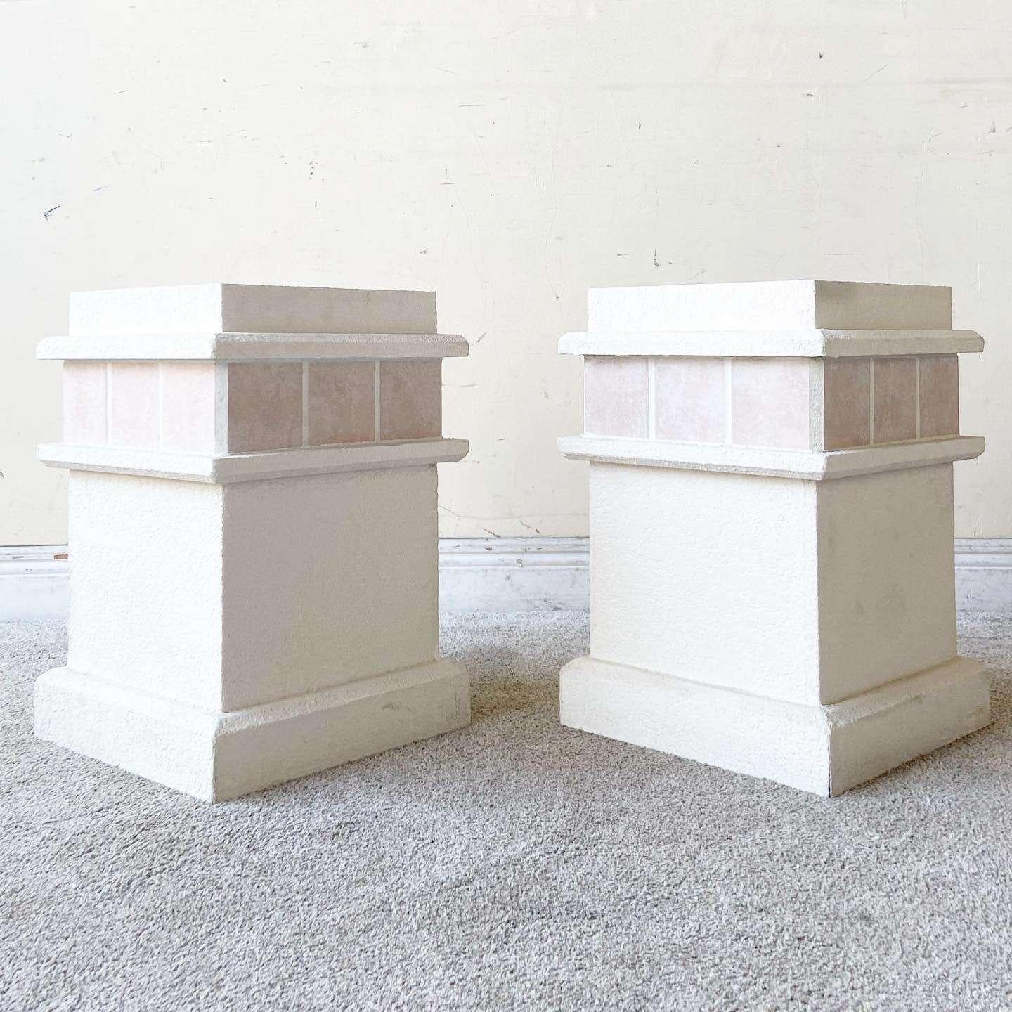 Amazing vintage postmodern pedestal side tables. Each feature a white stucco finish with a pink ceramic tile border.