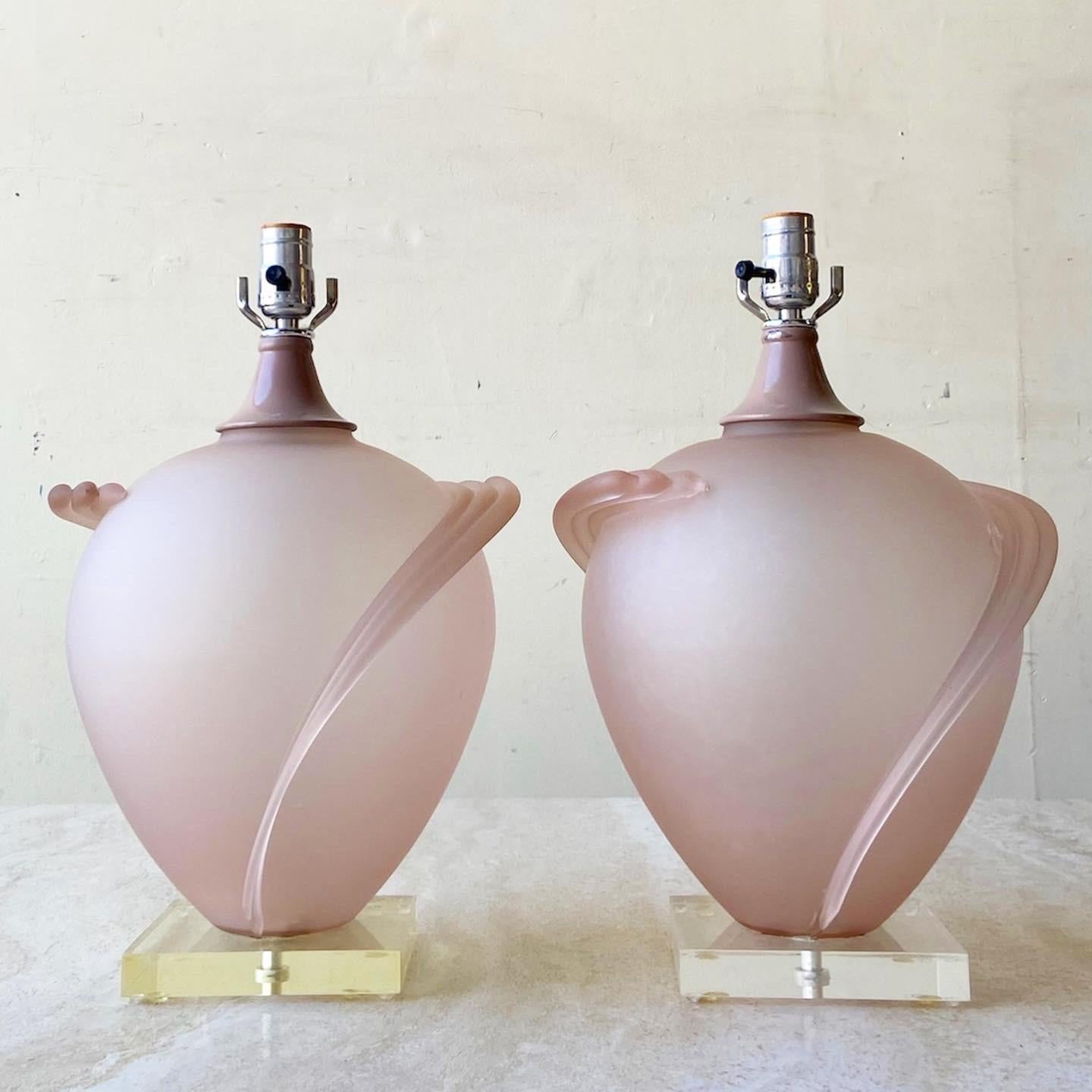 Incredible postmodern pair of table lamps. Each feature a sculpted pink glass body with wings on a lucite base.
