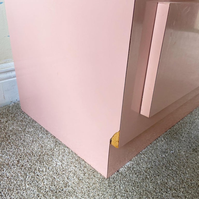 Incredible pair of postmodern nightstands. Each feature a pink lacquer laminate with gold Paneling and gold faux bamboo drawer pulls.
 