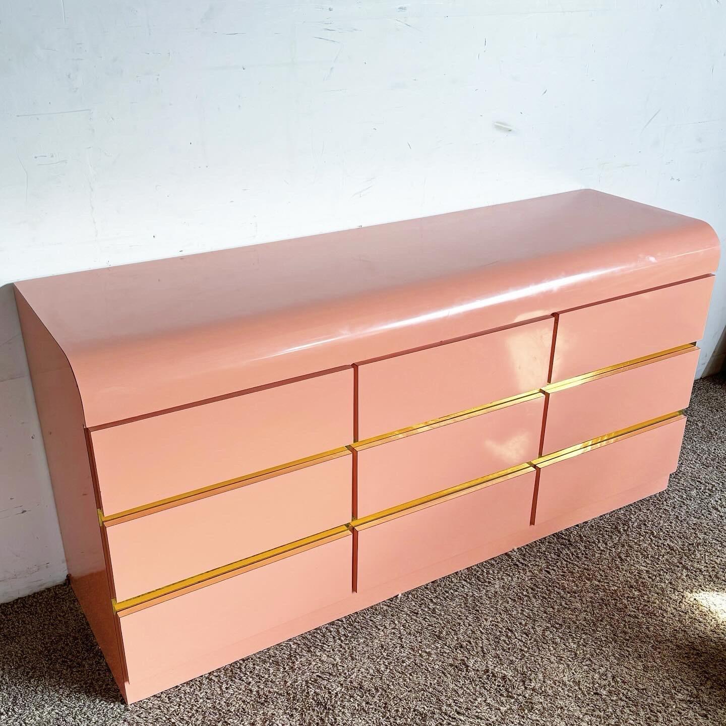 Embrace the vibrant postmodern style with the Pink Lacquer Laminate Waterfall Dresser, featuring gold accents. This piece combines bold color and sleek design, offering ample storage and a statement look for any room.