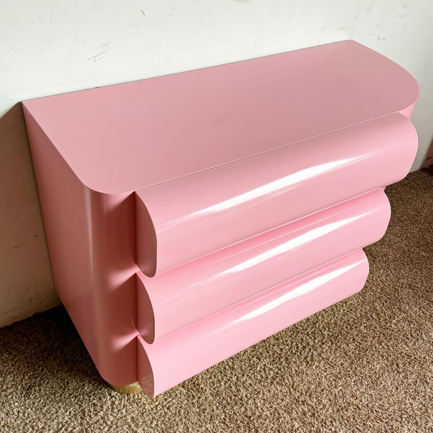 Transform your space with the Postmodern Pink Lacquered Curved Bullnose Commode/Chest of Drawers. This piece boasts a unique curved design and a vibrant pink lacquer finish, creating a modern and playful statement. The smooth bullnose edges enhance