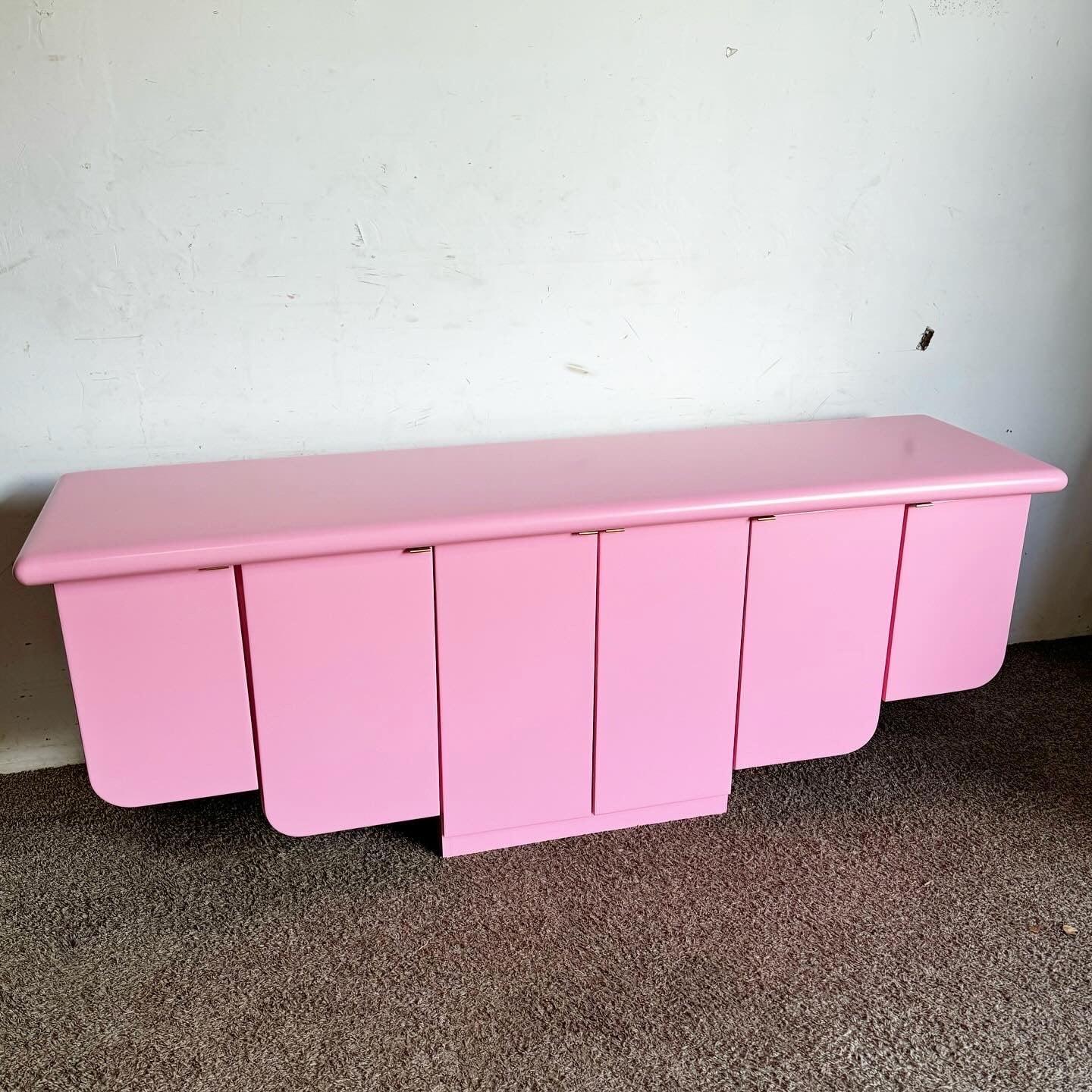 Add a splash of chic to your interior with this Postmodern Pink Scalloped Credenza. Featuring a unique scalloped design, elegant gold handles, and a floating design, this piece combines style and functionality. Perfect for modern and eclectic decor,