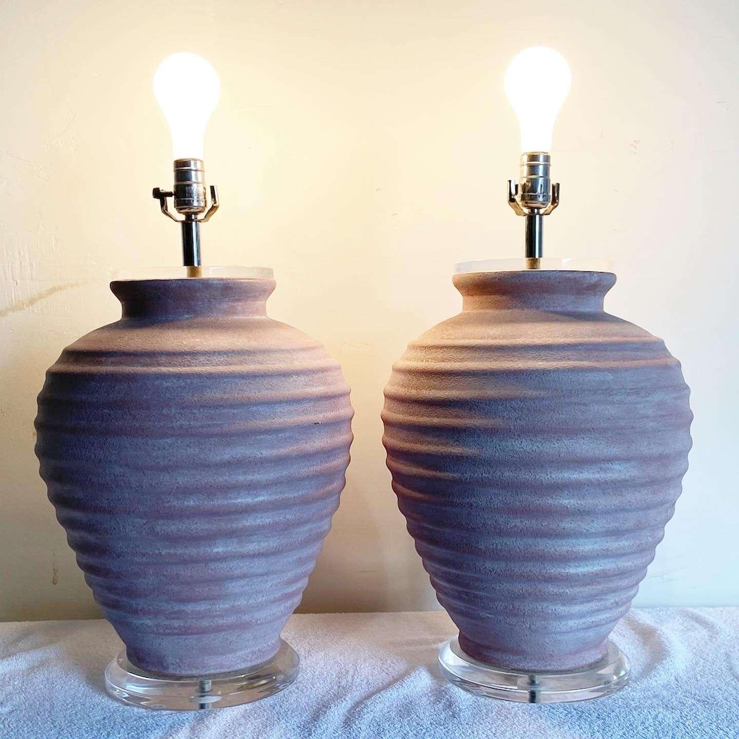 Superbe paire de lampes de table en céramique. Chacune d'entre elles présente un lavis rose sur un corps nervuré avec un disque en lucite en dessous et au-dessus de la céramique.